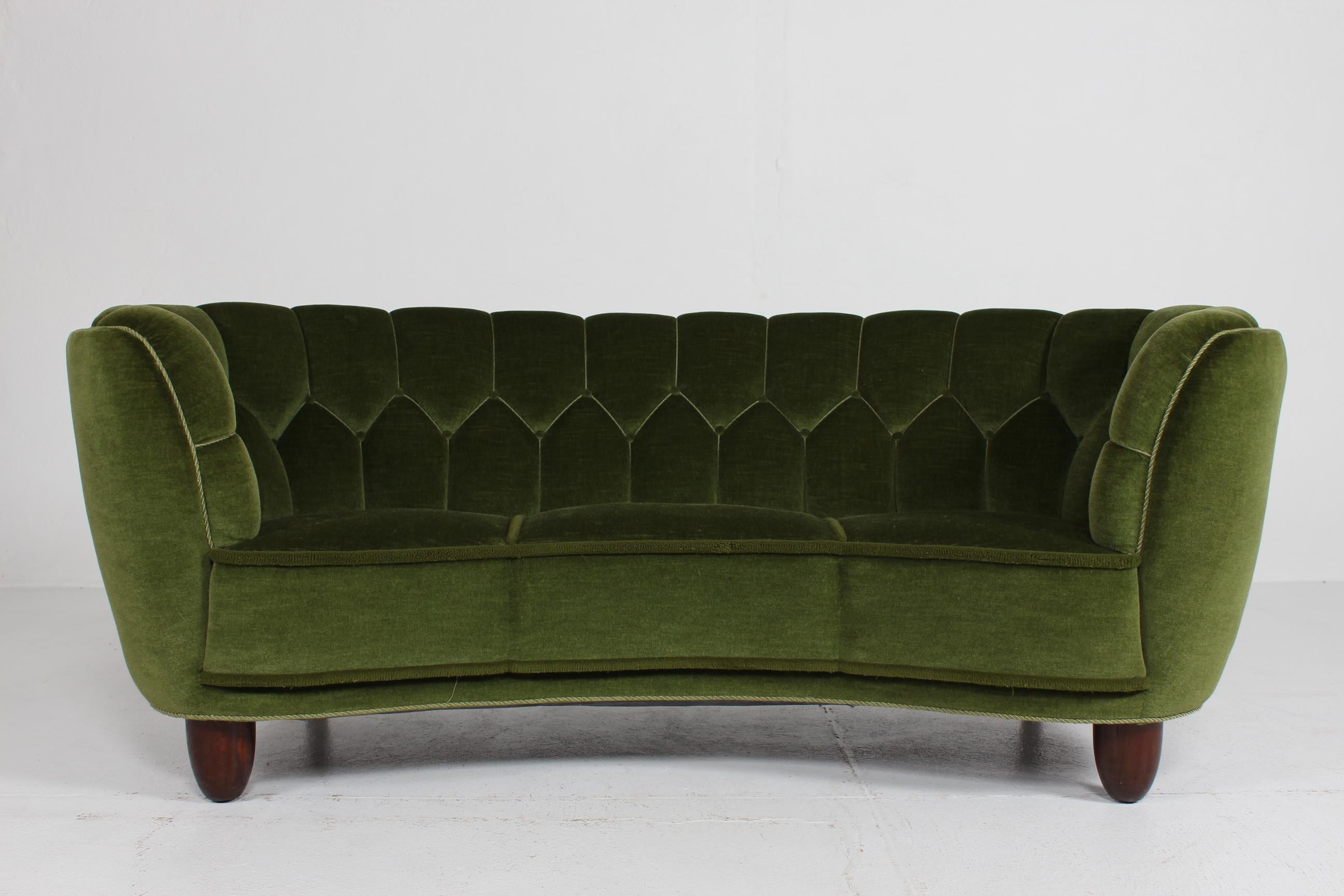 Danish curved, banana shaped Art Deco couch/sofa.
The legs are made of dark stained oak and the sofa is upholstered with dark green velvet.
Danish carpenter handmade and tightly upholstered by a very skilled furniture upholsterer in the 1940s. 

The