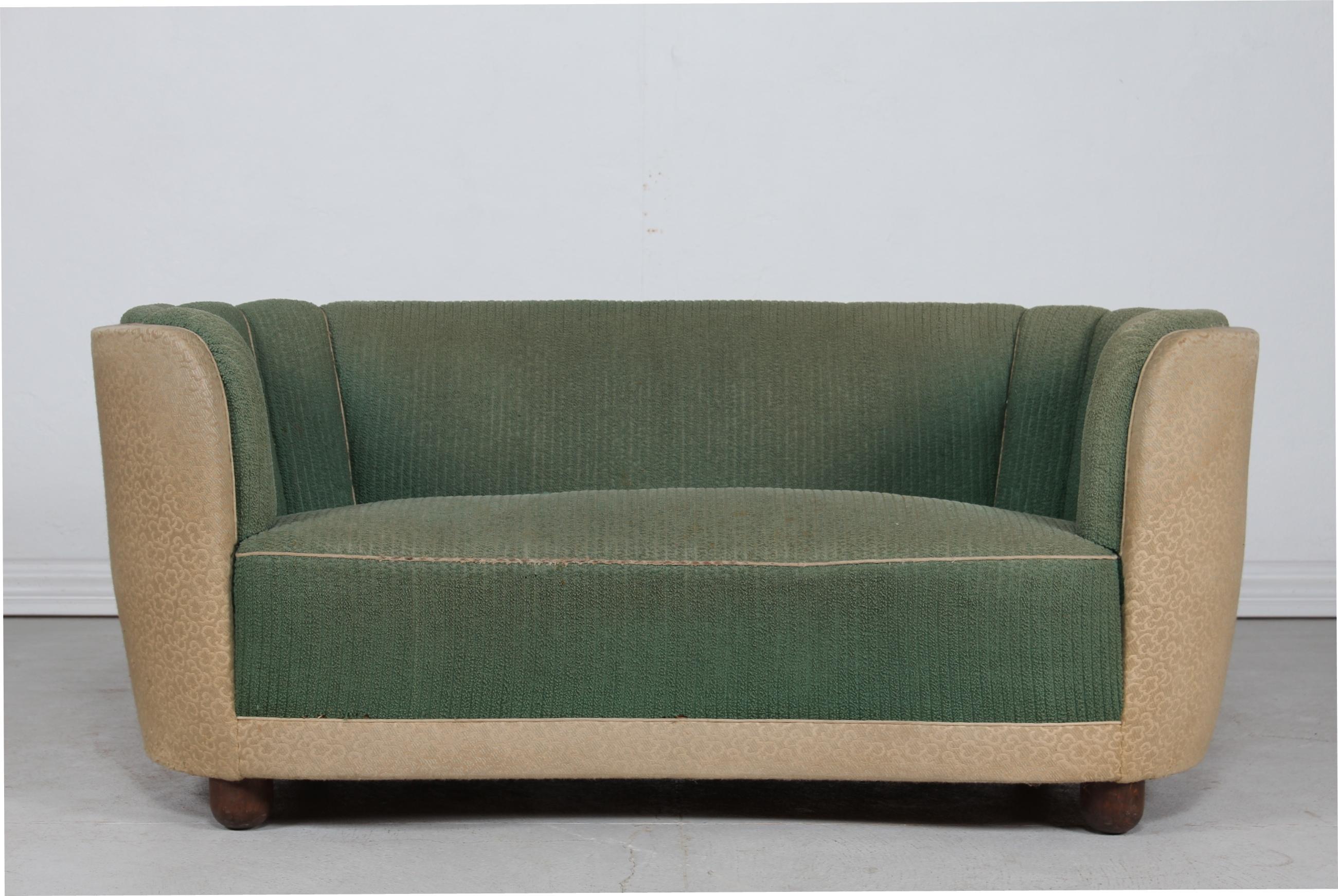 Danish curved Art Deco couch or sofa from the 1930s.
The legs are made of dark stained wood and the sofa is upholstered with dusty green and light fabric.
Made by Danish furniture maker in the 1930s. 
It is most likely manufactured by Slagelse