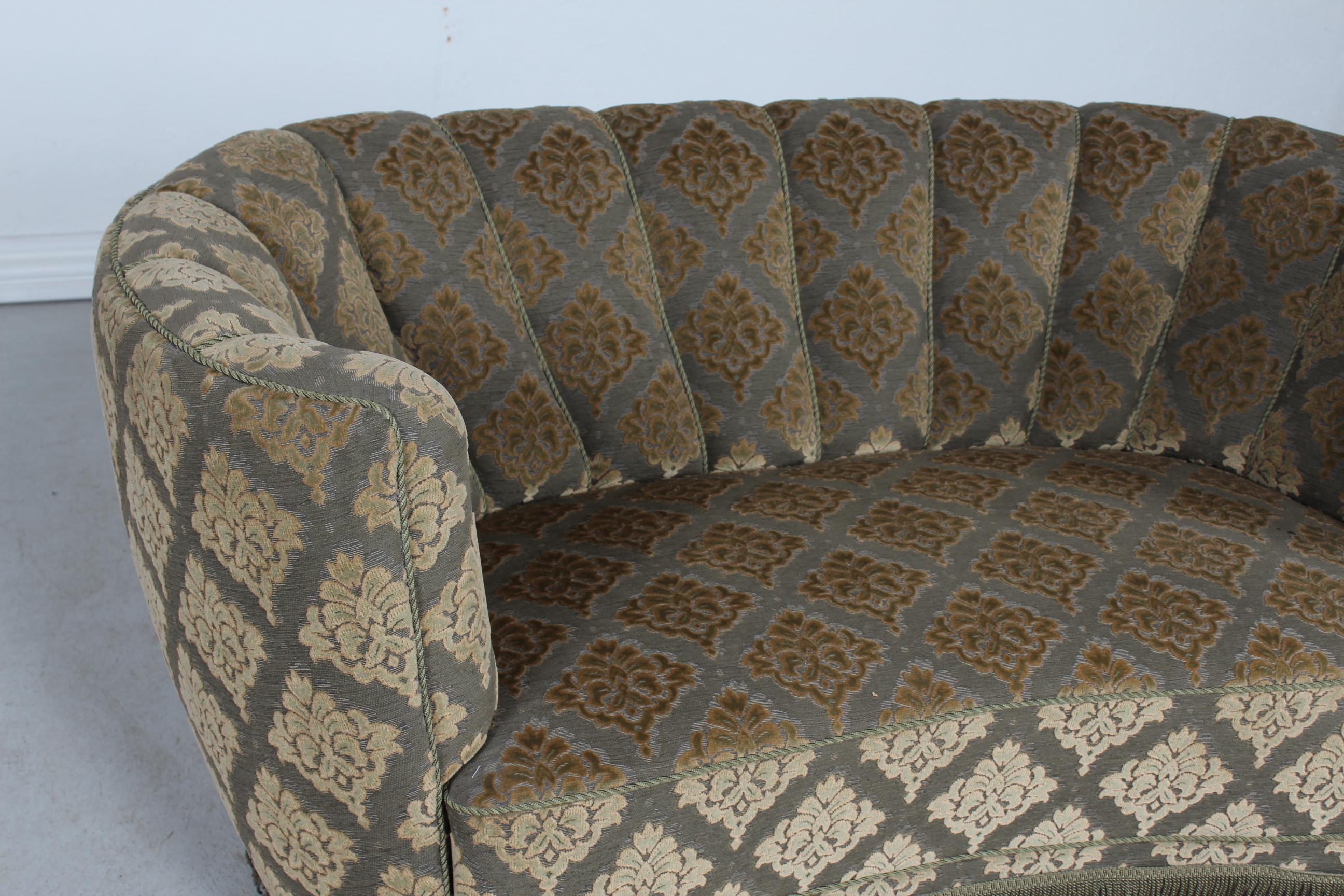 Danish curved Banana form Art Deco couch or sofa made in the 1950s.
The legs are made of dark stained wood and the sofa is upholstered with green velour/velvet with floral pattern and fringes.
Made by Danish furniture maker in the 1950s. 

The