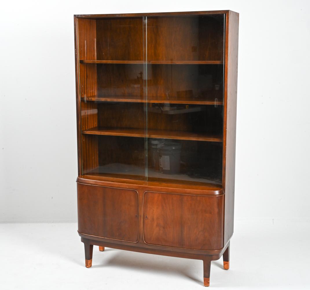 Capture the luxurious spirit of the Art Deco Period with this rare bookcase cabinet, designed and produced by the Danish firm Georg Kofoed Møbelfabrikant around 1930-1940. 

This gorgeous piece boasts a streamlined silhouette, with a curved front