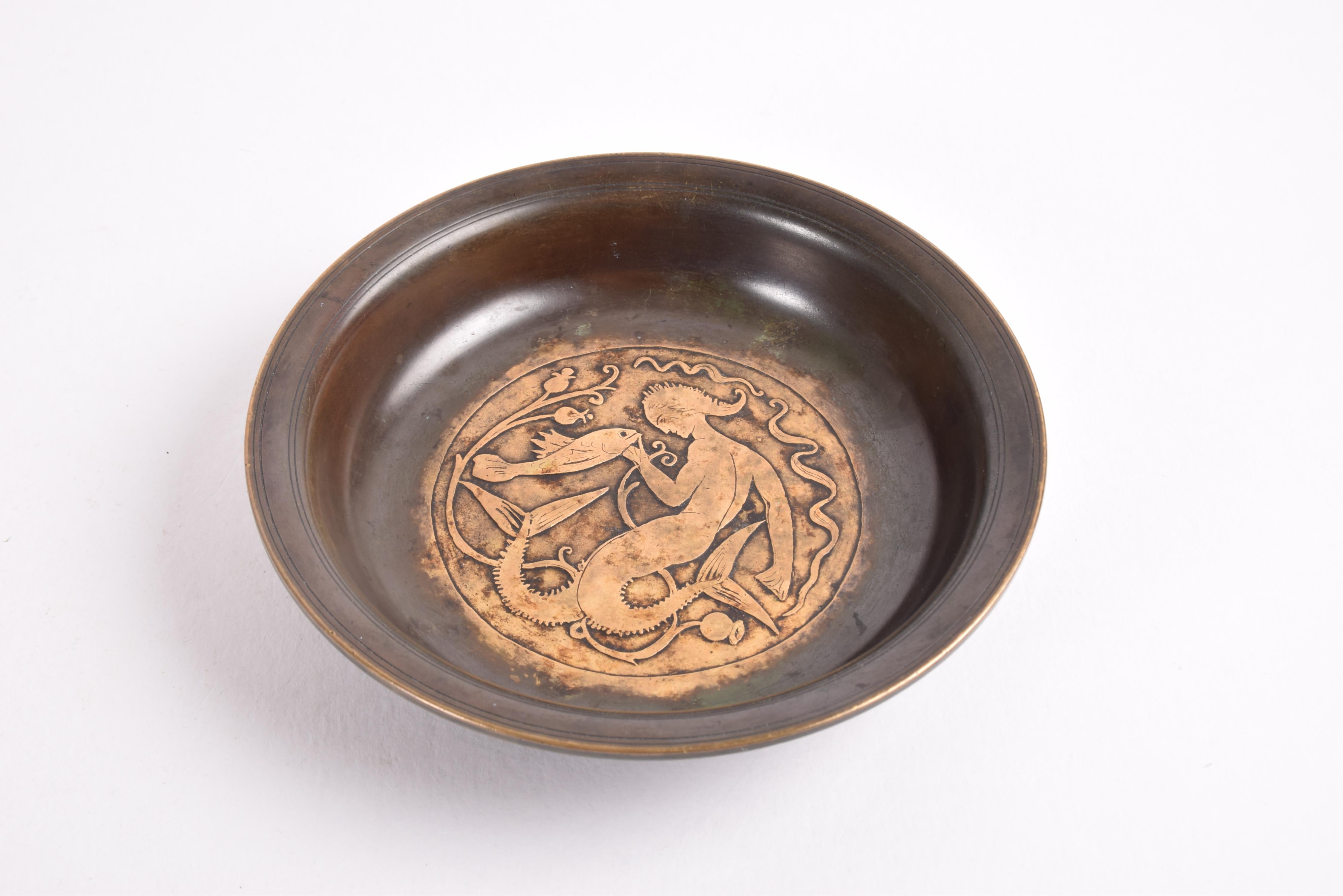 Decorative Art Deco dish from Just Andersen (1884-1943) made in the 1930s. It's made from bronze with brown patina.
Decorated with a stylized mermaid, a fish and water flowers.

Signed with monogram for Just Andersen and B96.

