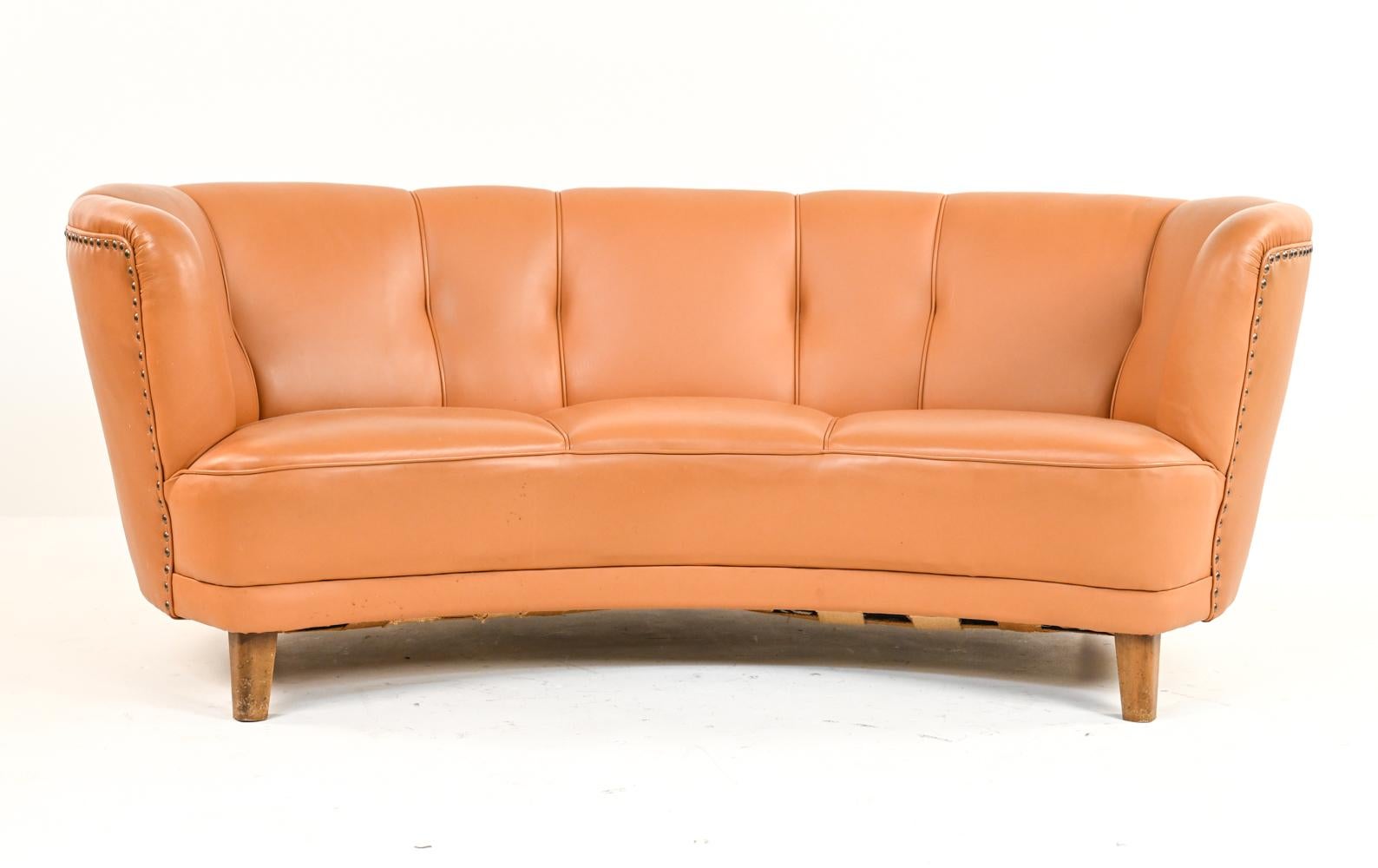 A handsome Danish Art Deco banana sofa in the manner of Viggo Boesen and Flemming Lassen's iconic designs. Featuring warm orange-toned leather upholstery with attractive nailhead trim detail, this banana sofa epitomizes the highly renowned