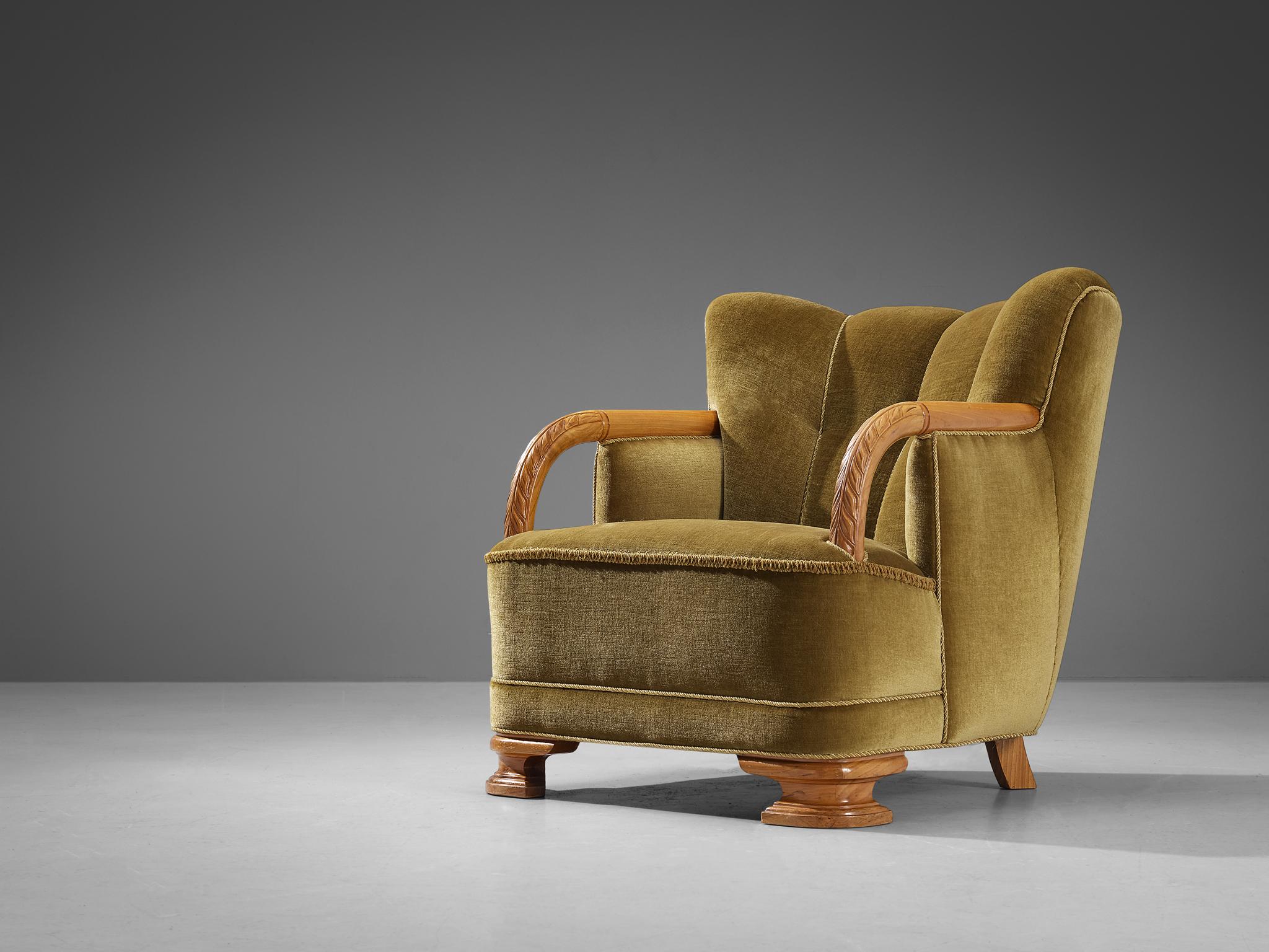 Easy chair, velvet, elm, Denmark, circa. 1940 

This lounge chair of Danish origin comes with an olive green velvet upholstery that beautifully blends in with the warm tone of the wooden frame executed in elm. The design is based on a solid