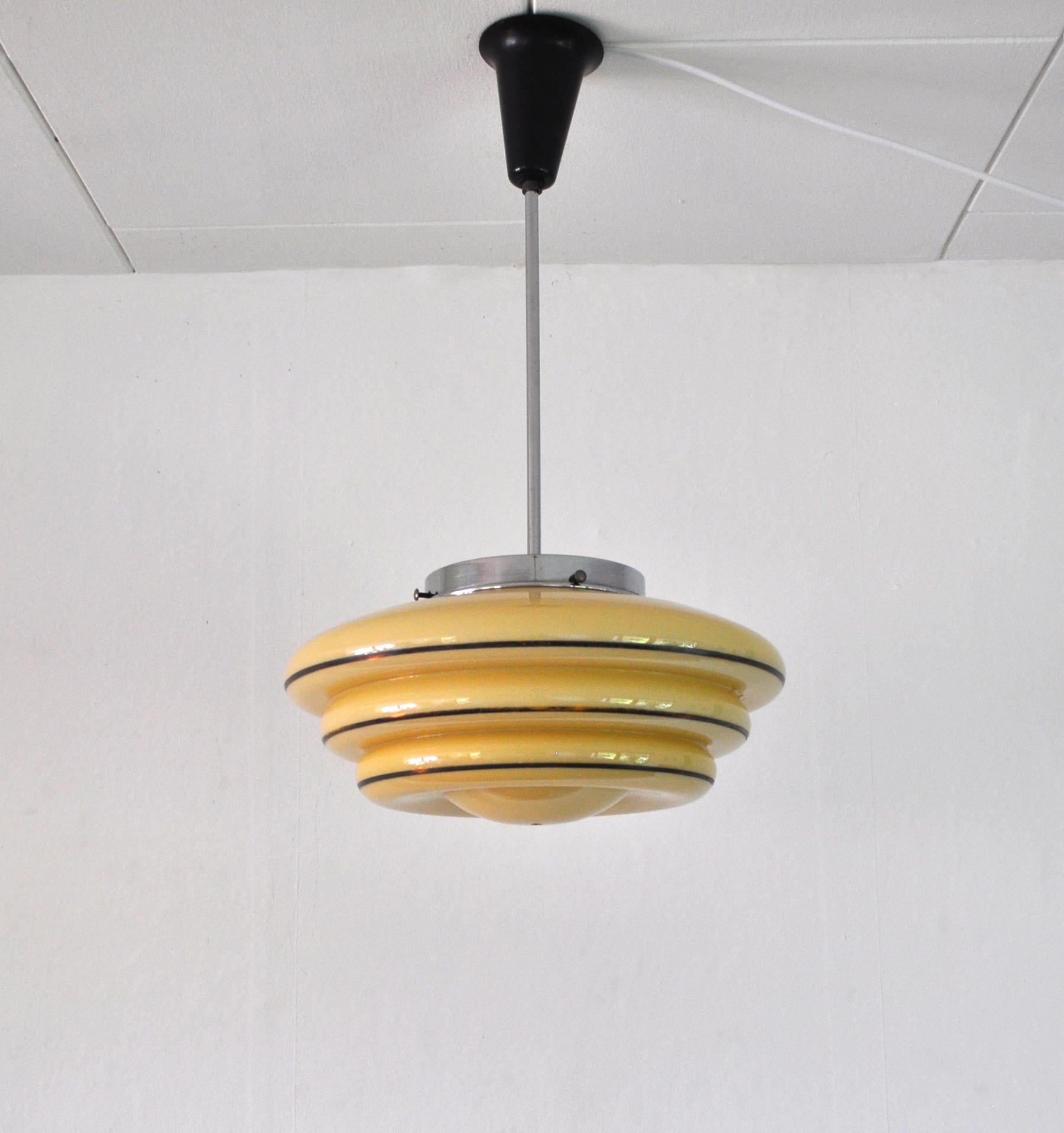 Danish Art Deco pendant lamp composed of fluted opaline glass with painted overlay stripes. Chrome Stem and original Bakelit canopy. Attributed to Lyfa in the 1930s.

Excellent condition.
Light source: E27 Edison screw fitting.
Dimensions: Full