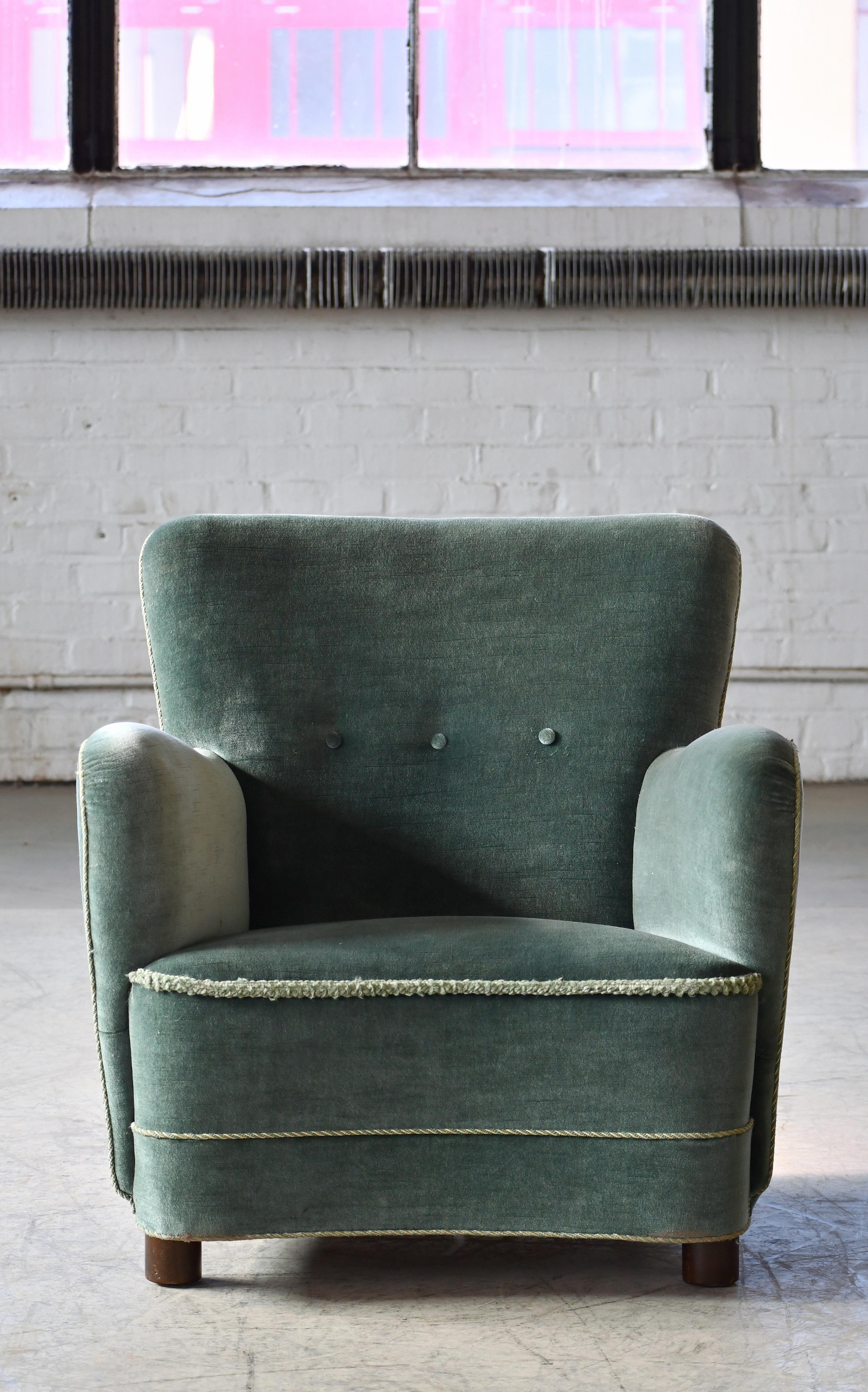Curvy and eye-catching Danish club chair from the 1930s or 1940s. Set on mahogany feet the design is typical of the art 