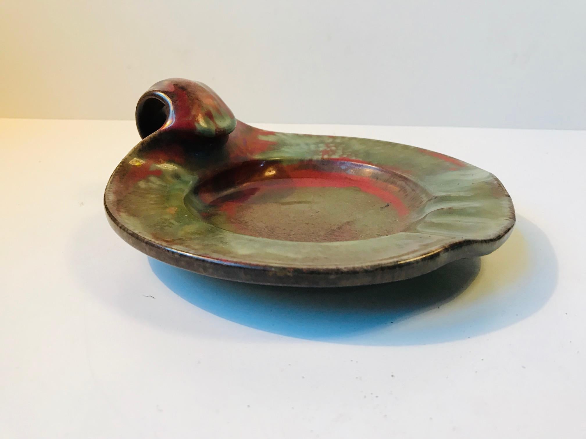 - A handled cigar ashtray in vibrant polychrome glazes
- Designed by the Danish ceramist Niels Peter Nielsen
- This piece was created at Dagnæs Keramik during the 1930s or 1940s 
- The style is reminiscent of Kähler and Michael Andersen.
- H: 6.5