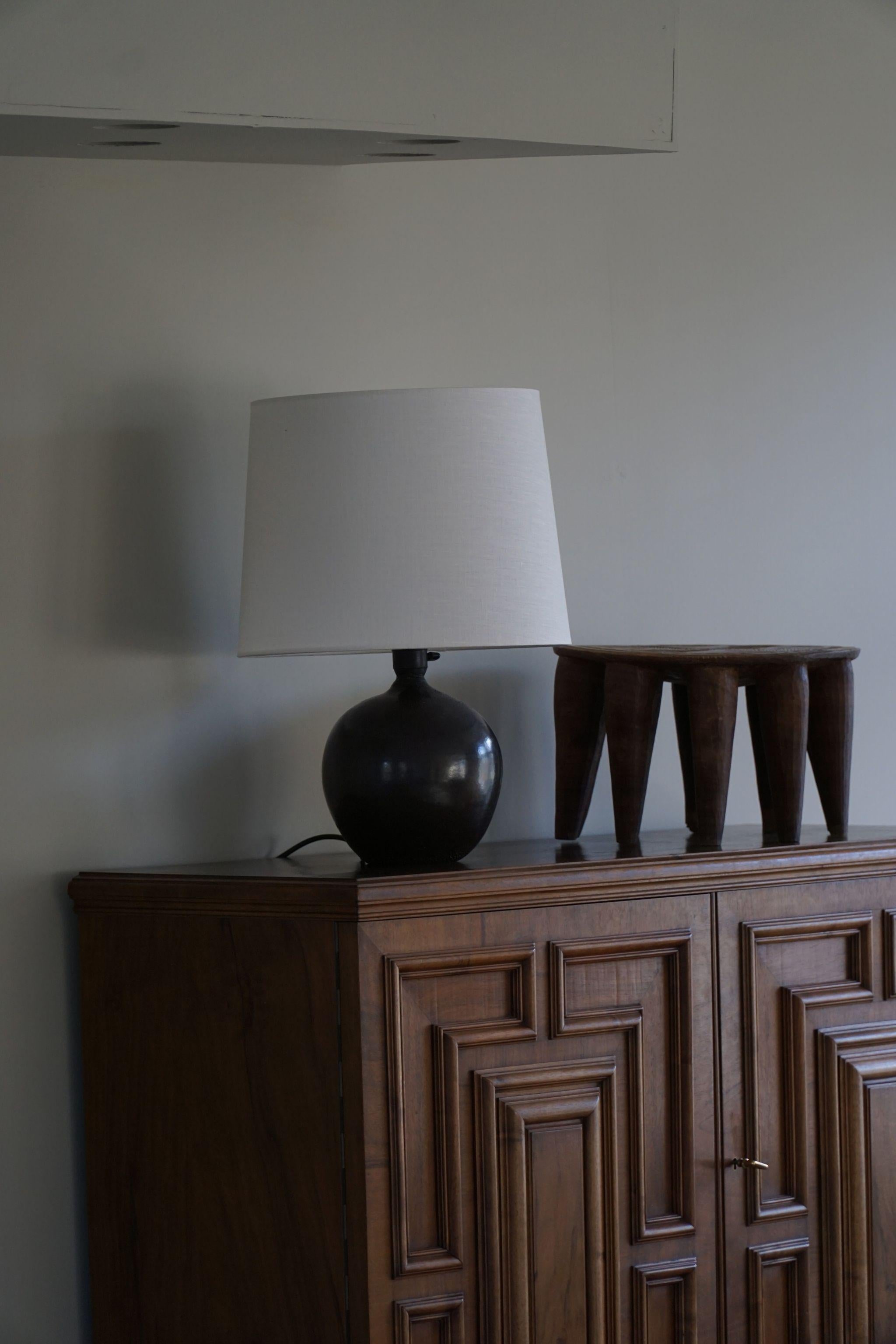 An early 20th century round ceramic table lamp with black glaze. Made in Denmark. A beautiful vintage object well suited for the modern interior. 

