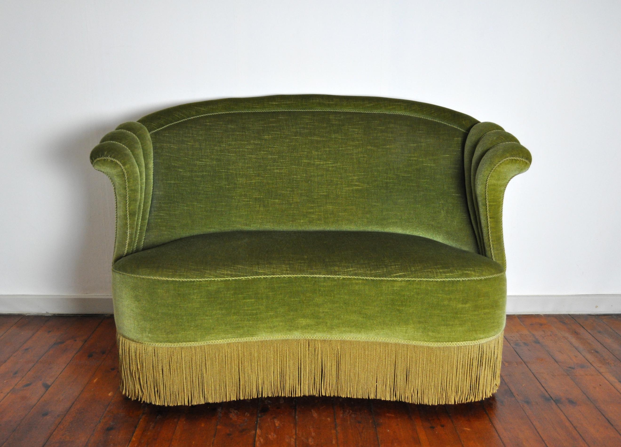Voluptuous Art Deco sofa executed with wooden legs, green velvet and fringes (can be removed). High lined and curved back and backrest.
It shows traits of traditional Victorian furniture yet also has a contemporary art deco touch.
Excellent