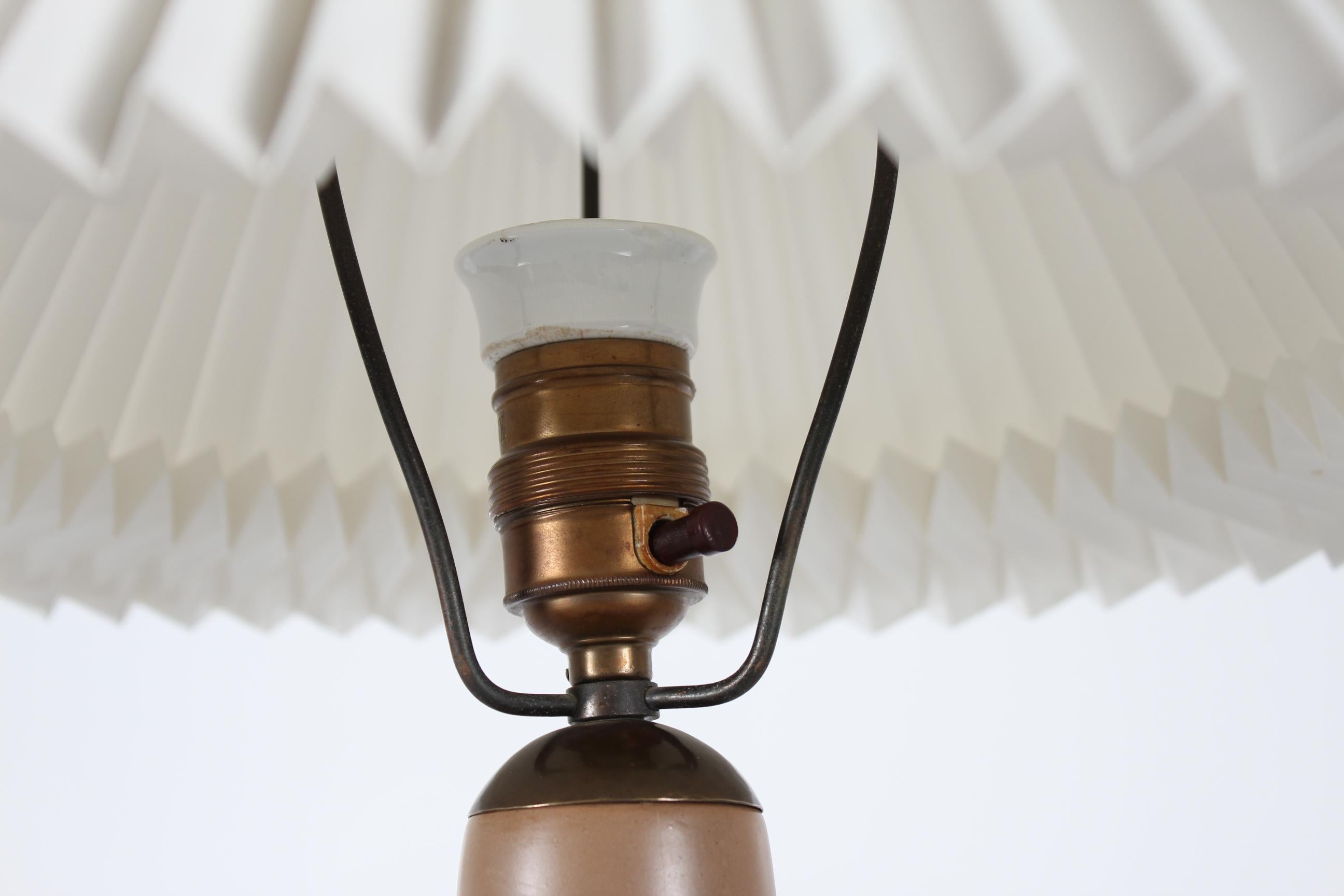 Lampe de table Art déco du studio de céramique danois L. Hjorth sur l'île de Bornholm.
La base de la lampe est en céramique brun moka clair, décorée de deux canards nageurs et de tiges. Les couleurs de la décoration sont le marron, le bleu verdâtre,