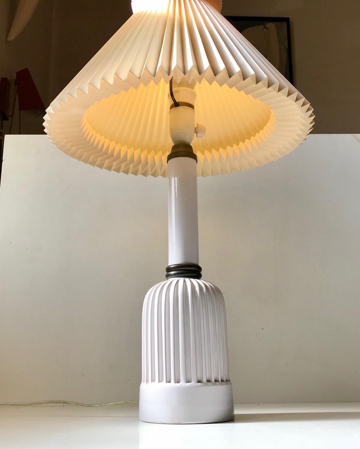 A rare and monumental version of the Danish Heiberg table lamp. It has a fluted - ribbed bottom part, bronze details and delicate white glaze to the out- and inside. It was designed and manufactured by Christian Schollert in Naerum Denmark during