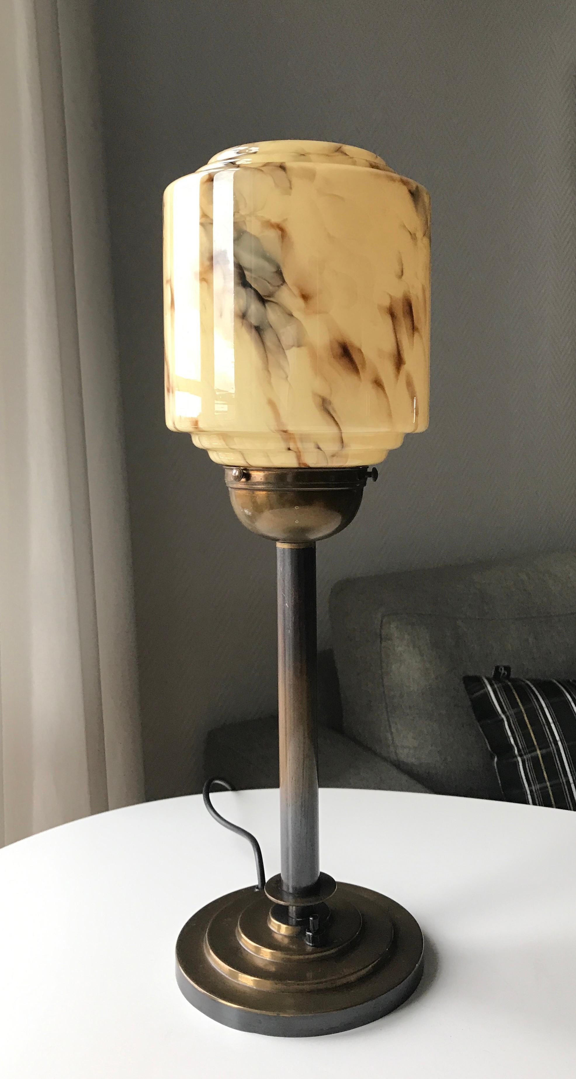 Danish early 20th century Art Deco table lamp manufactured by Voss. Typically design from the period between early 1920s-end 1950s. Dark patinated brass plinth with on/off switch. Tube in brass with patinated sunburst effect fading from dark to