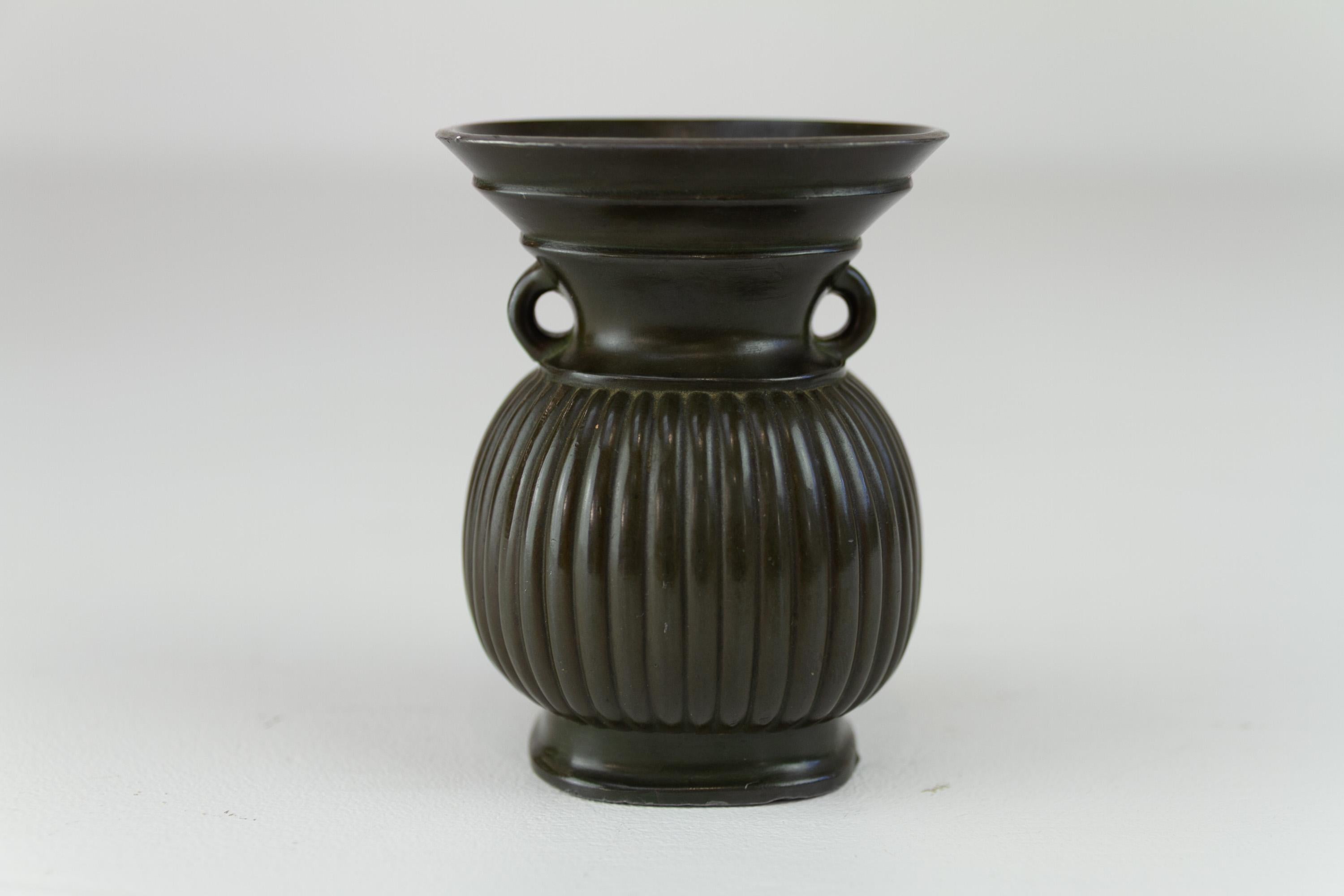 Vaso danese Art Deco in metallo Disko di Just Andersen, 1930.

Piccolo vaso o urna Art Déco con corpo scanalato e due manici. Realizzato in Danimarca da Just Andersen con il suo marchio Diskometal. 

Marchio del produttore e numero di modello