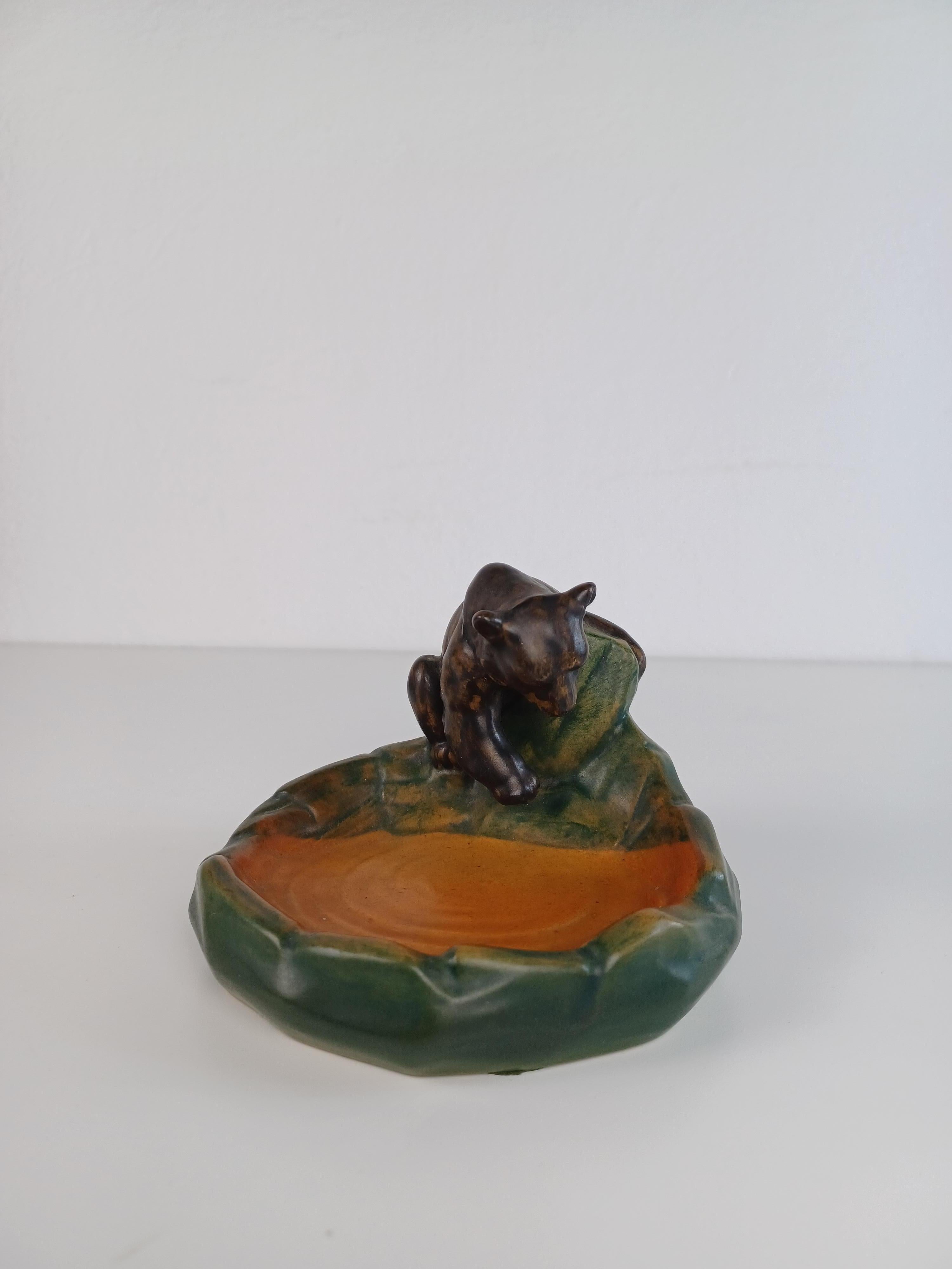 Portacenere / ciotola in stile Art Nouveau danese disegnato da Axel Sørensen nel 1939 per P. Ipsens Enke.

Il portacenere/ciotola art nuveau presenta un orsetto vivace ben realizzato a mano che cerca di pescare in un lago ed è in buone condizioni