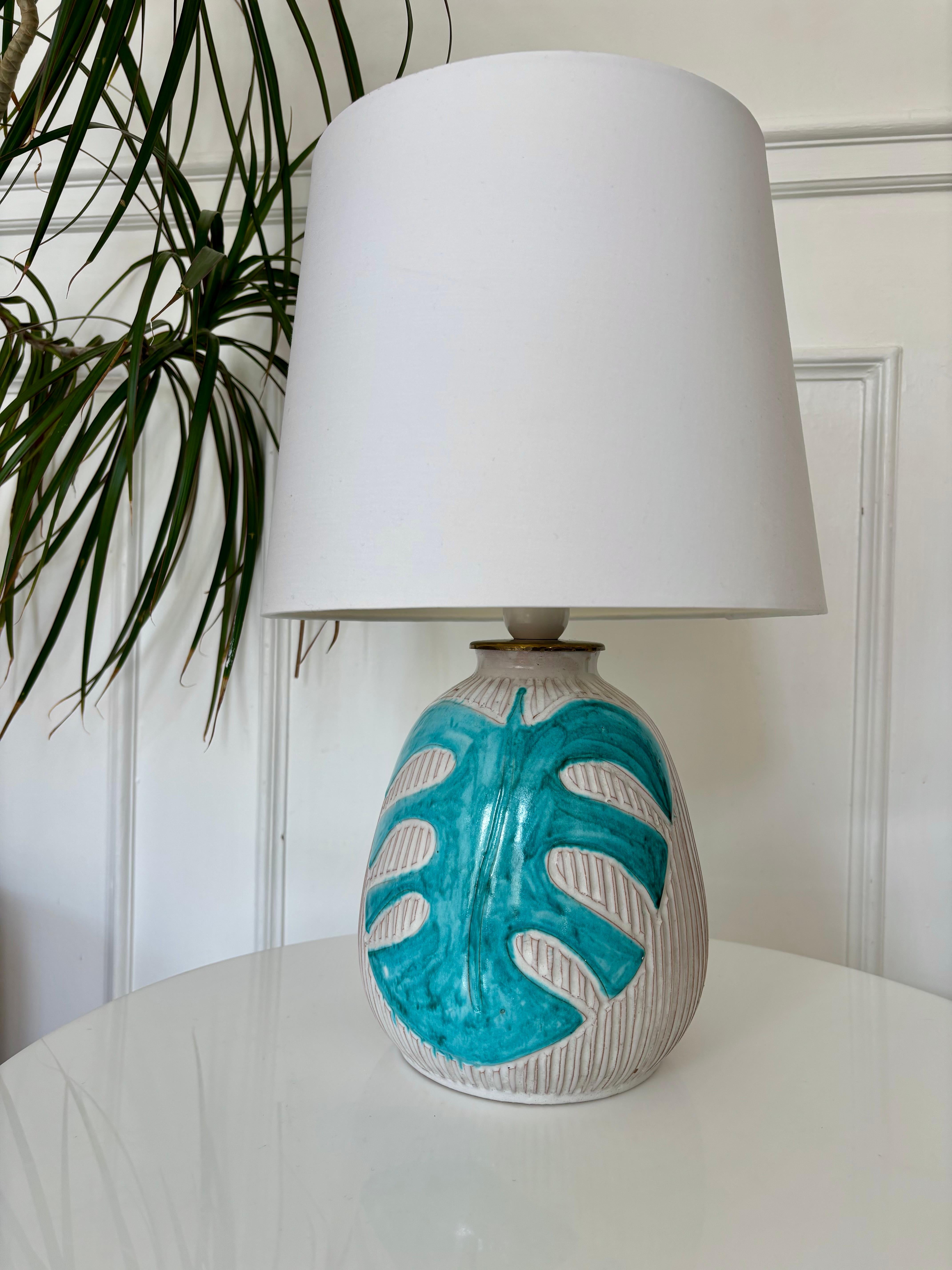 Lámpara de sobremesa de cerámica Art Nouveau en relieve blanca forrada de esmalte blanco crema con grandes hojas estilizadas de color verde turquesa. Con cable para uso en la UE y EE.UU. con enchufe escandinavo. Montaje con interruptor.
Pieza de 80