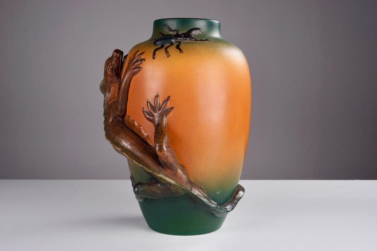 Danish Art Nouveau lizard vase by Lauritz Jensen for Ipsens Enke in 1899.

The art nuveau vase that feature a very well made lively lizard on the frontside of the vase chasing a beetle cravling on the side of the vase is in excellent