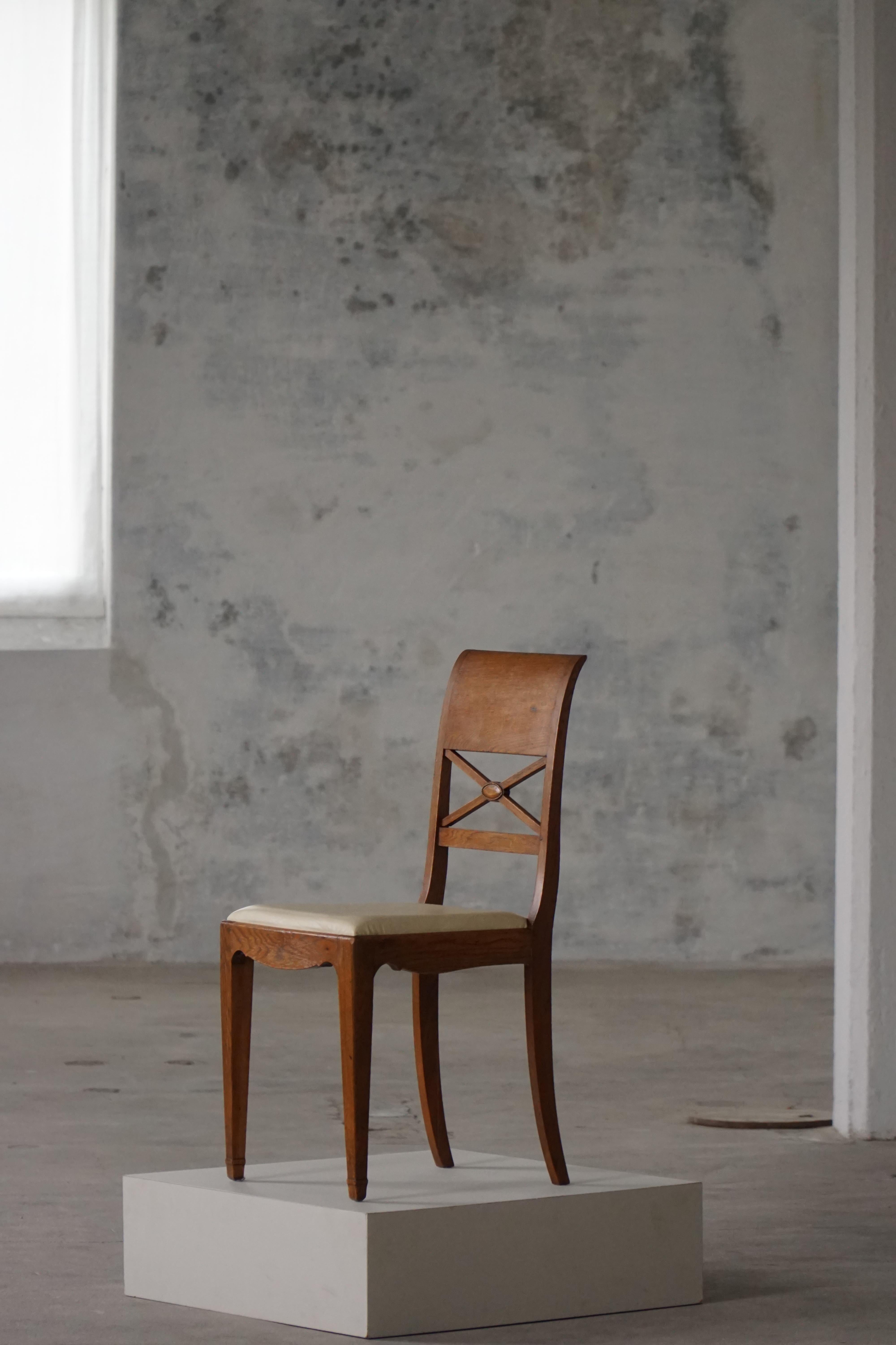 Un grazioso set di otto sedie da pranzo danesi, realizzate in quercia negli anni '20-'30 circa. Il design fonde influenze classiche con una raffinata lavorazione Art Nouveau, con schienali curvi e un'elegante stecca incrociata con un medaglione