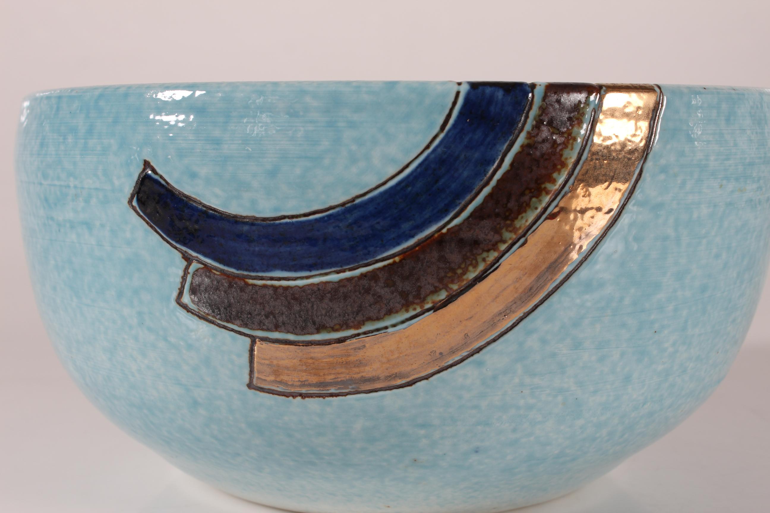 Large artistic bowl made by the danish artist Tue Poulsen (born 1939)  in his own studio.  

The bowl has a base with light blue glaze and a single stripe-decoration of midnight blue, brown and gold colours.

The bowl is signed on bottom: Tue 

Very