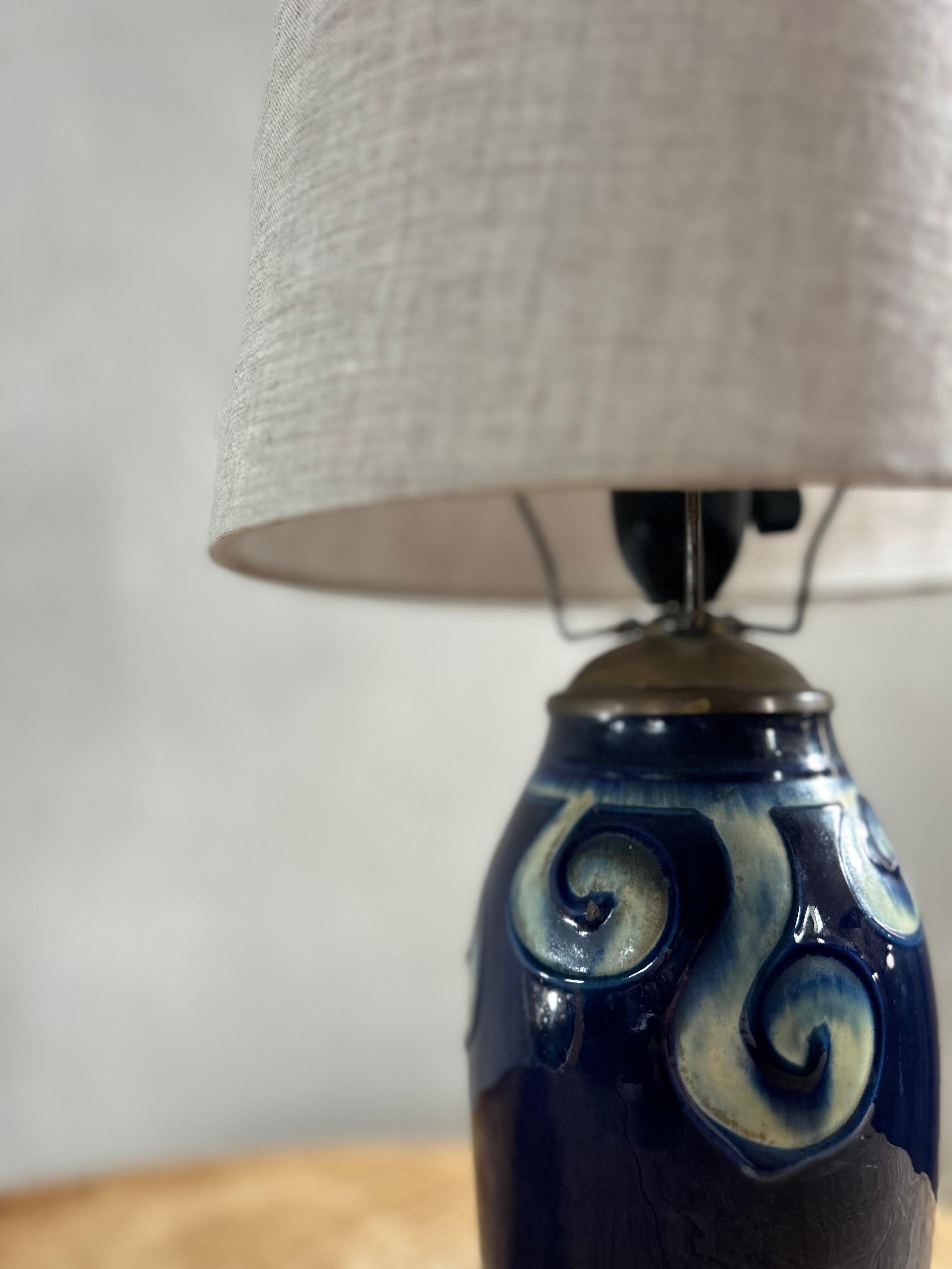 Beleuchten Sie Ihren Raum mit dem Charme und Charakter des dänischen Arts-and-Crafts-Designs mit dieser exquisiten antiken Keramik-Tischlampe, die in den 1910er Jahren in Dänemark entstand. Diese mit viel Liebe zum Detail und mit Hingabe an die
