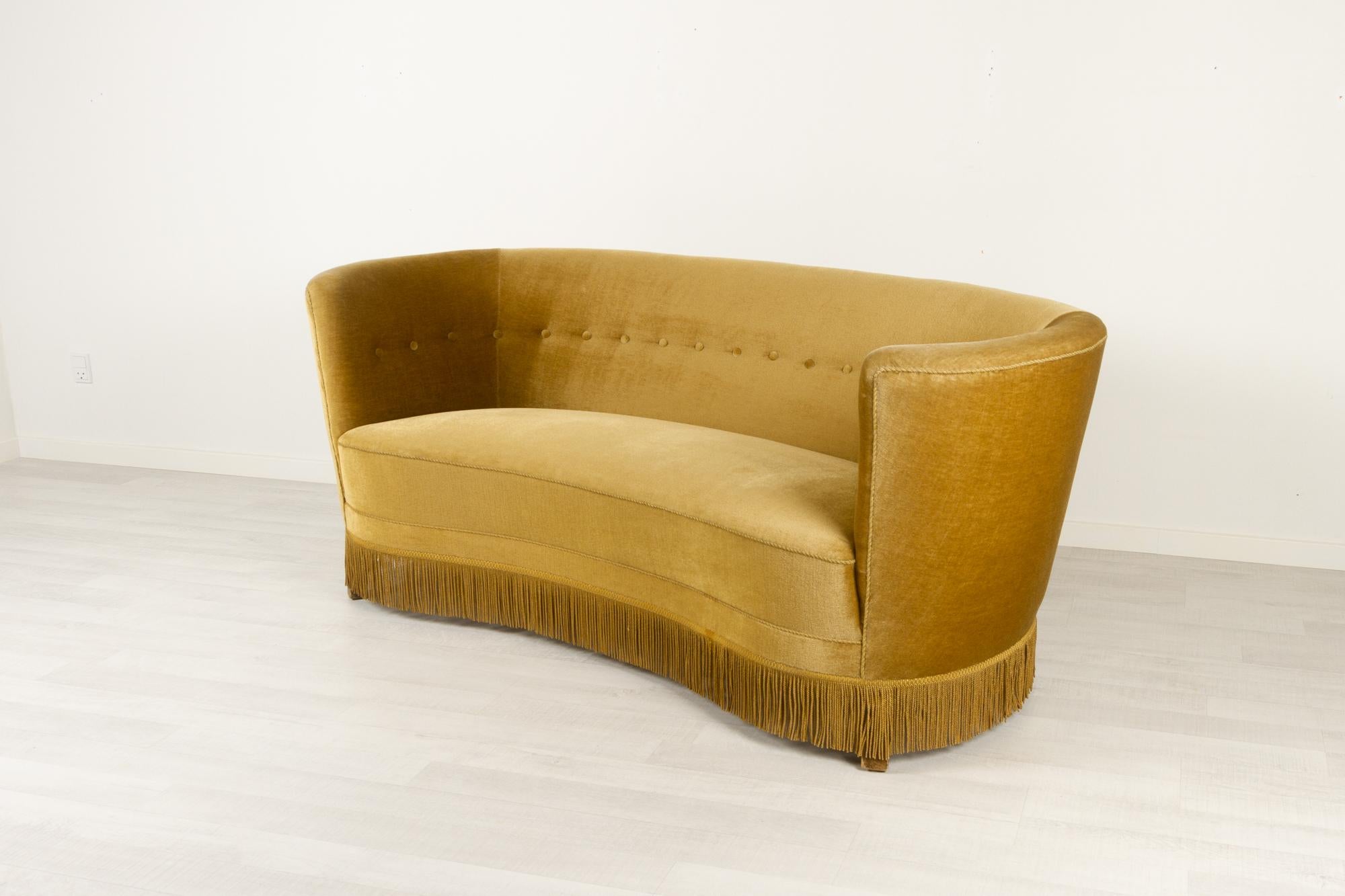 Danish banana sofa, 1940s
Vintage Danish banana-shaped loveseat upholstered in green/beige/gold velvet. Curved two-seater with original spring and velour upholstery, base edged with fringes. Feet in stained beech.
Very good original condition.