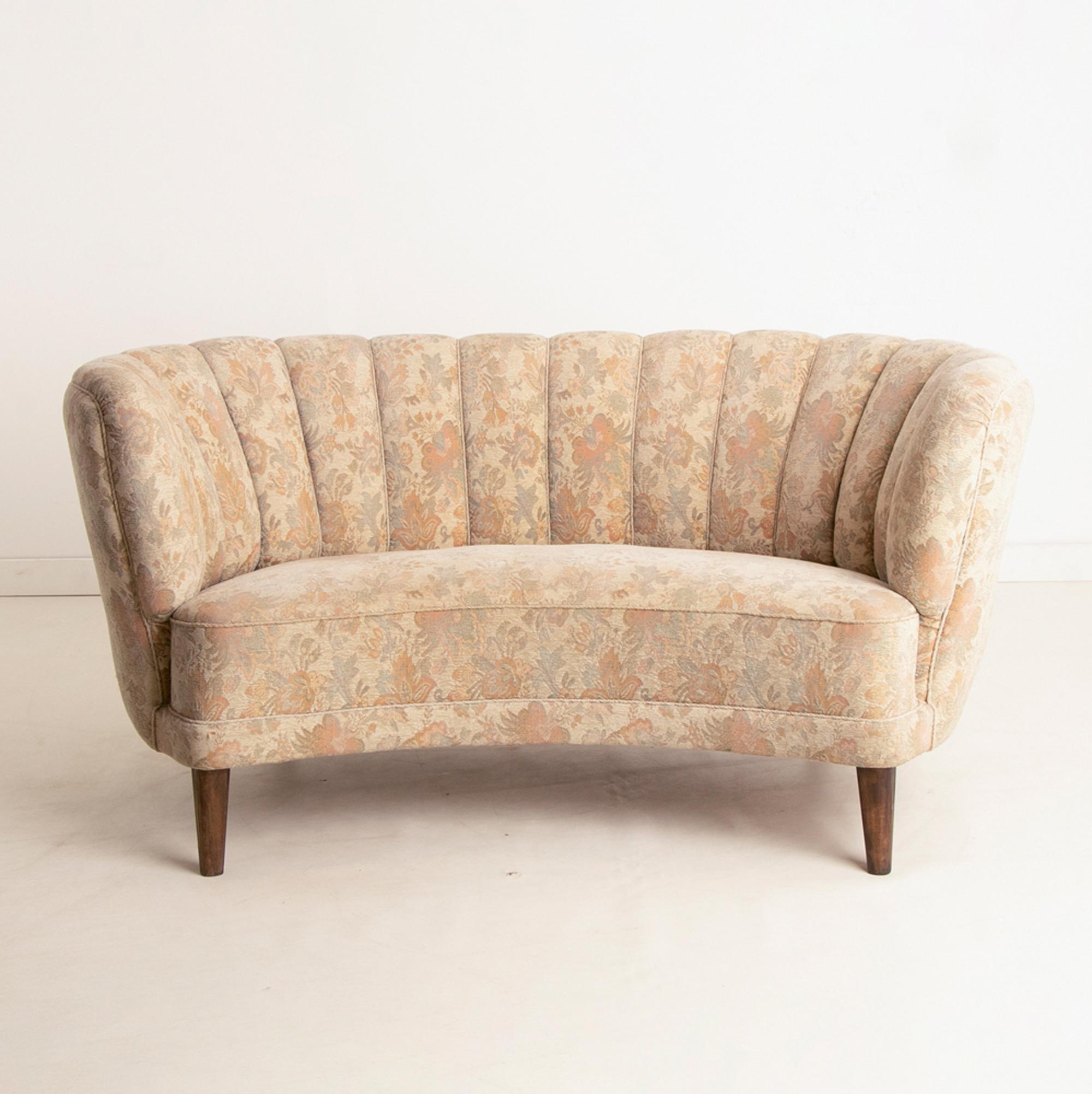 A vintage Danish banana sofa with a stylised curved back and floral upholstery.

The sofa is comfortable and home ready.