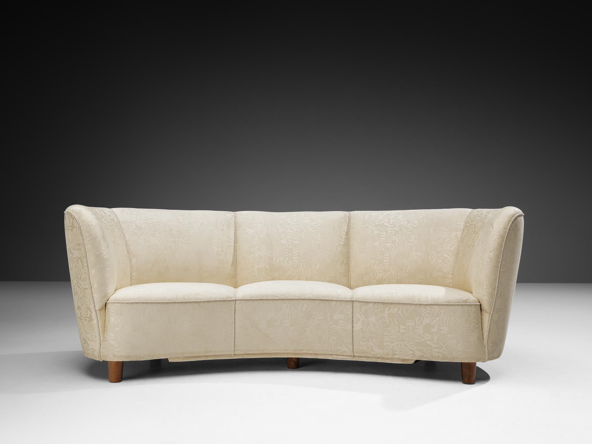 Banana sofa, off white upholstery, wooden legs, Denmark, 1940s.

This voluptuous sofa is executed in a wonderful off white fabric with a special looking pattern in it. The sofa has a high lined and curved back, while the backrest is horizontal