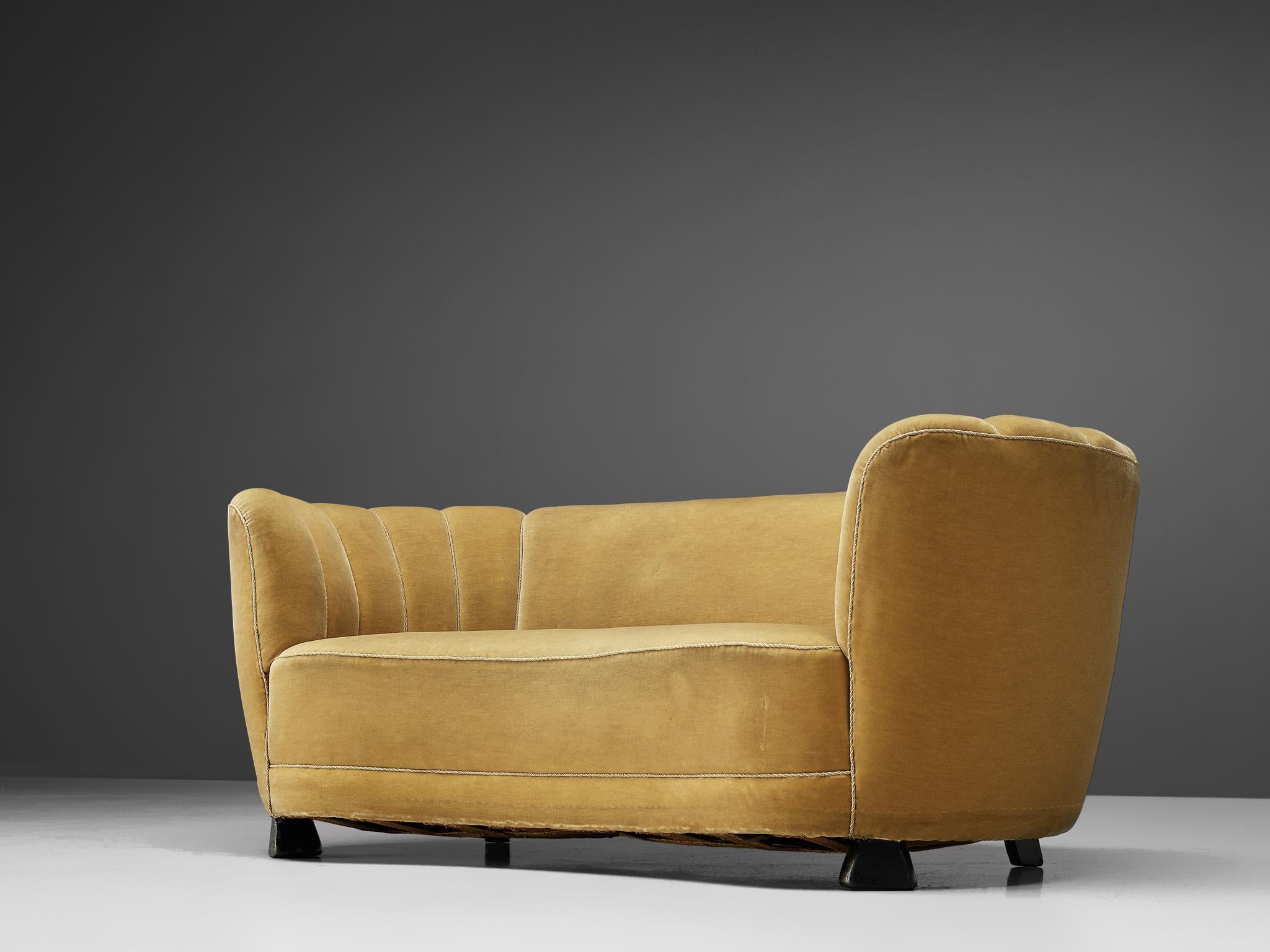 Banana sofa, mustard yellow velour upholstery and oak, Denmark, 1940s.

This voluptuous sofa is executed with a mustard yellow velour upholstery. The sofa has a high lined and curved back, while the backrest is horizontal straight and flows over