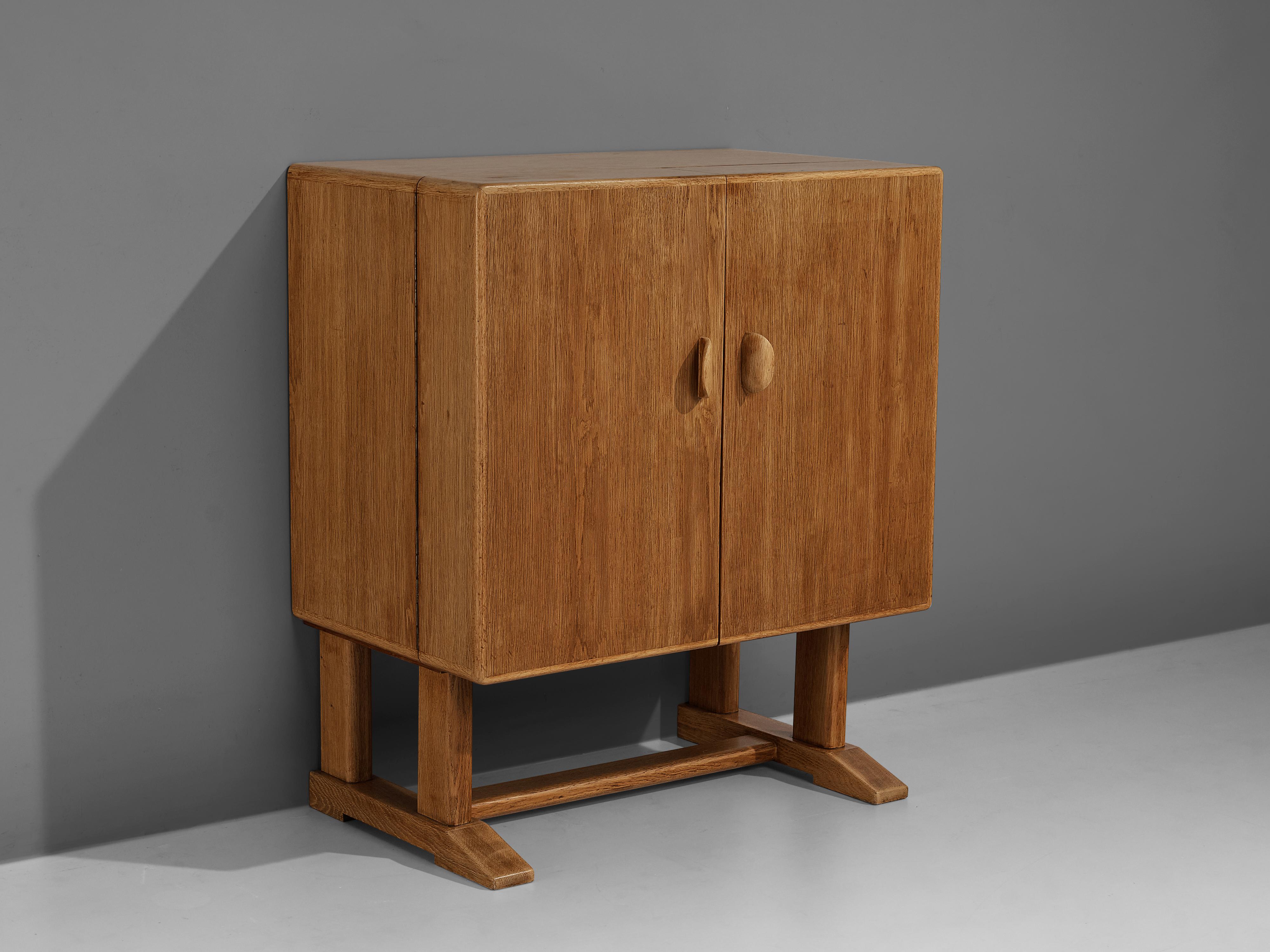Bar cabinet, oak, glass, Denmark, 1960s

Sturdy Danish bar cabinet in solid oak. The cubic cabinet rests on two paired legs with an interconnective slat. Two decorative, carved handles access the inside. Multiple functional storage facilities are