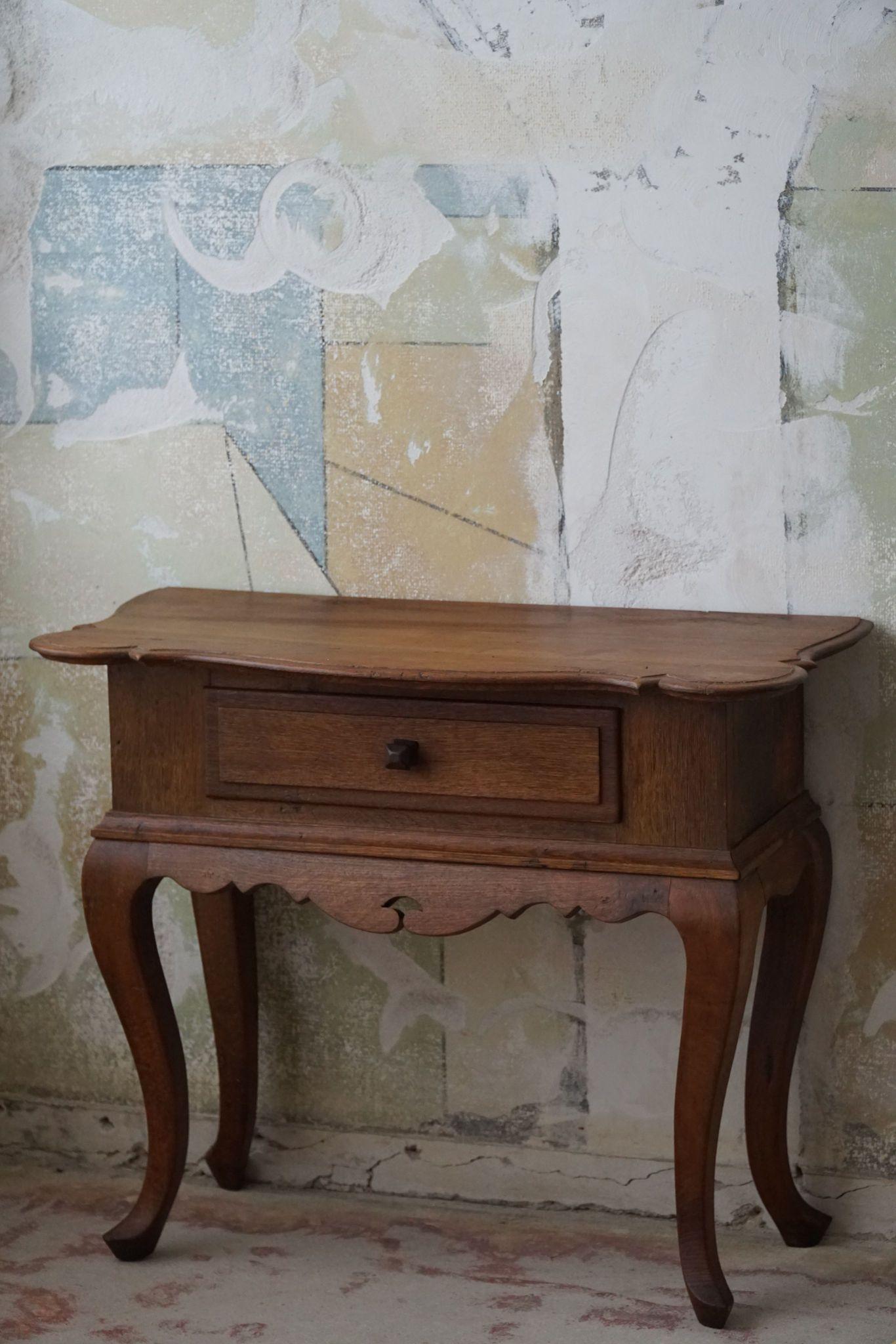 A charming entry table / console table with a drawer, crafted in the 1920s by a skilled Danish cabinetmaker, a stunning piece of furniture exuding elegance and craftsmanship. Carved from solid oak, this table boasts intricate details typical of the