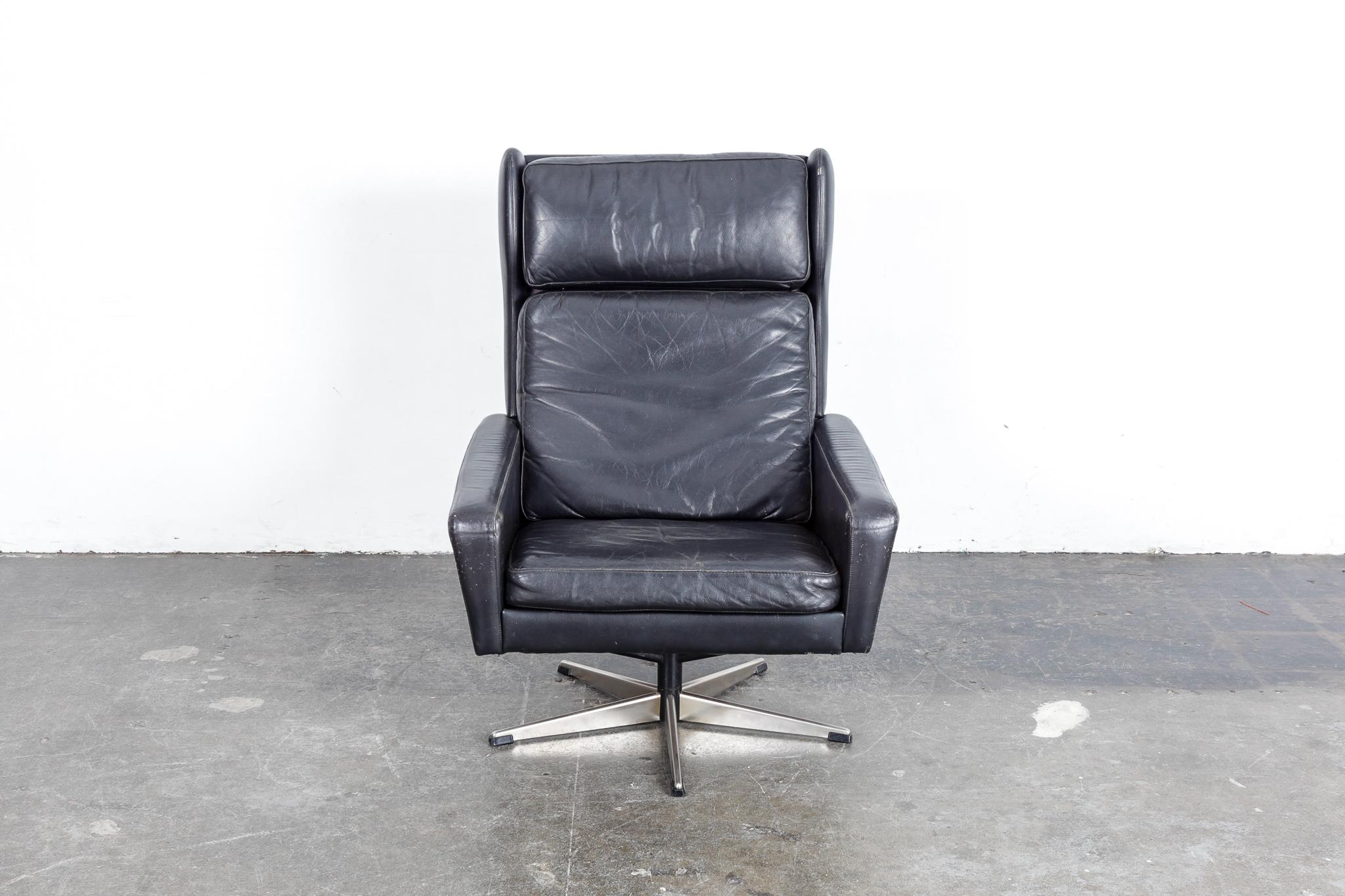 Classic Danish Mid-Century Modern original black leather swivel lounge chair, 1960s. 3 loose cushions for seat, back and head rest, in a wingback style tall chair. Leather shows patina and wear consistent with age but has no tears or gouges.