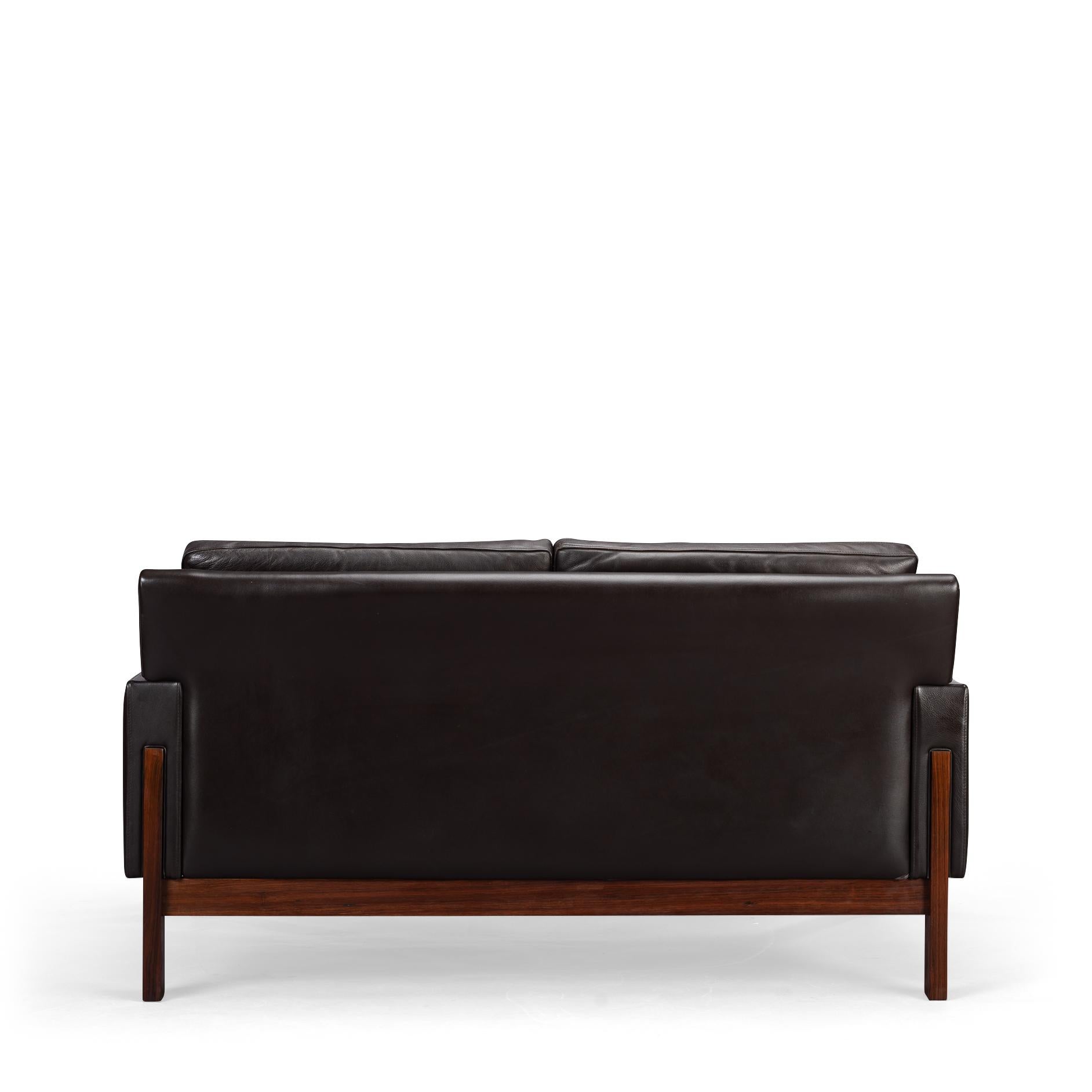 Black as night, faster than a shadow but also remarkably comfy folks! This mid century Danish sofa by Dux with base and legs in a deep dark rosewood has a lot going for it. Pure craftsmanship and durability to start with that are showcased by a