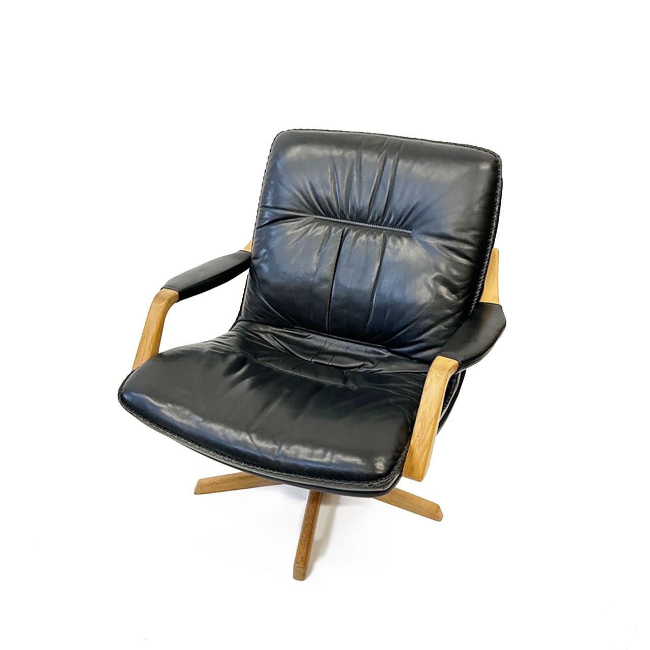 Wurde in den 1970er Jahren von Berg Furniture in Dänemark hergestellt. Gepolstert mit schwarzem Leder mit Peitschenstichbesatz und natürlicher, schöner Patina. Das Gestell und die Armlehnen sind aus Eichenholz gefertigt. Qualität, Design und Komfort