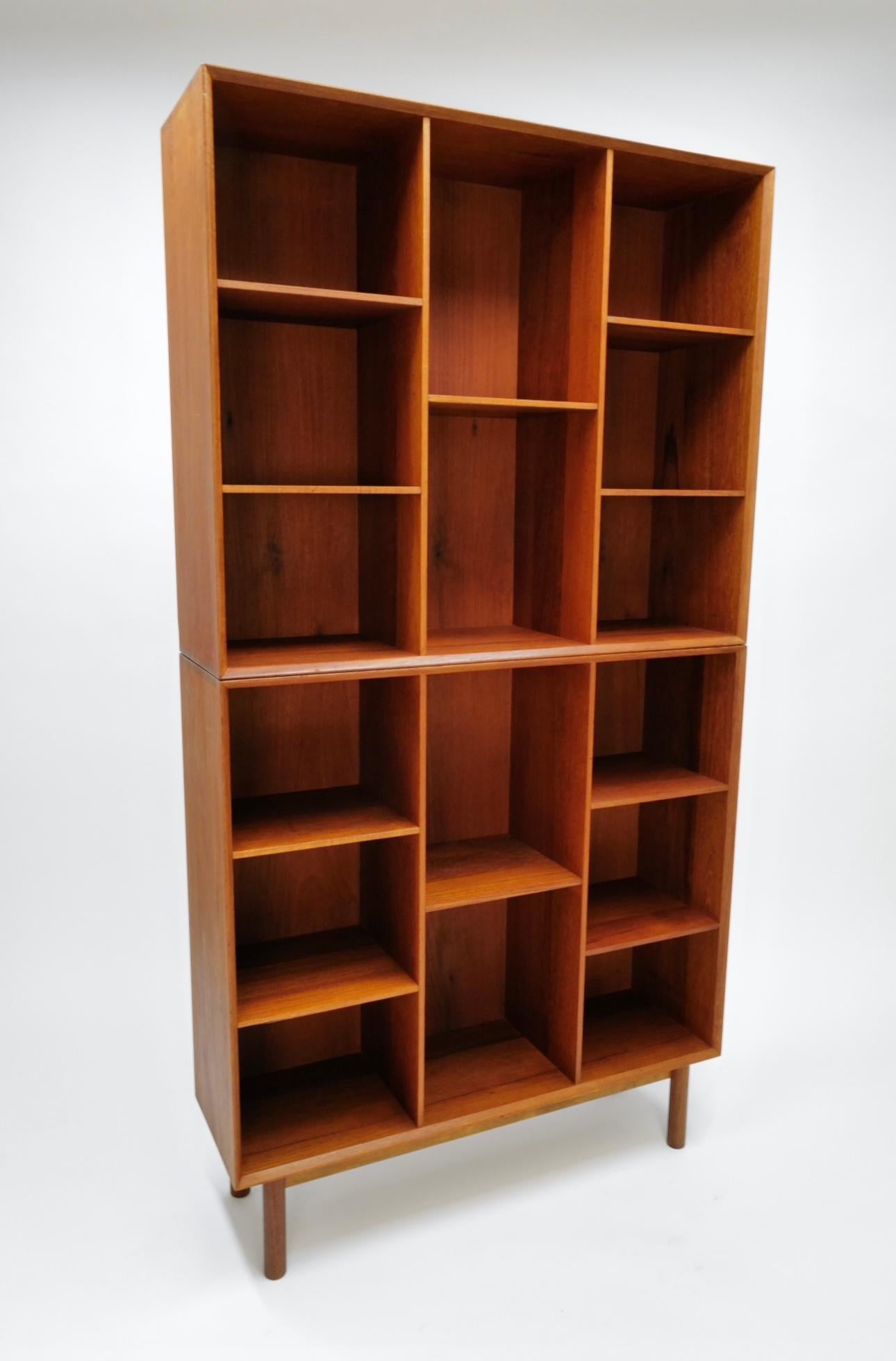 The two-piece stacking teak bookcase by Peter Hvidt and Orla Mølgaard-Nielsen for John Stuart Inc. epitomizes a harmonious blend of form and functionality. Meticulously crafted from luxurious teak wood, this modular bookcase features two distinct