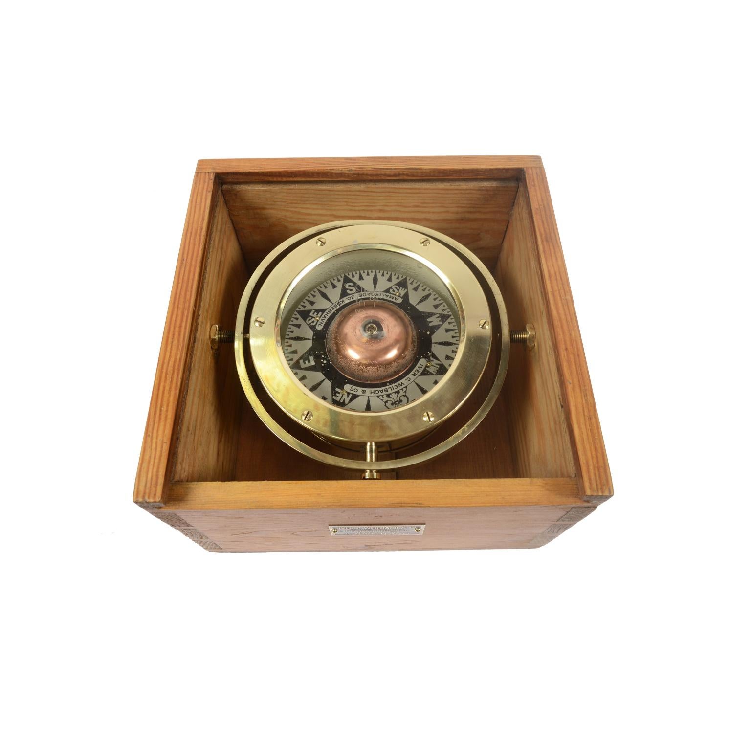 Magnetic compass on universal joint in its original wooden box with slot lid, produced by Iver C. Weilbach & Co Amaliegade 30 Copenhagen. The compass consists of a cylindrical vessel of brass and bronze, called a mortar, on the bottom of which is