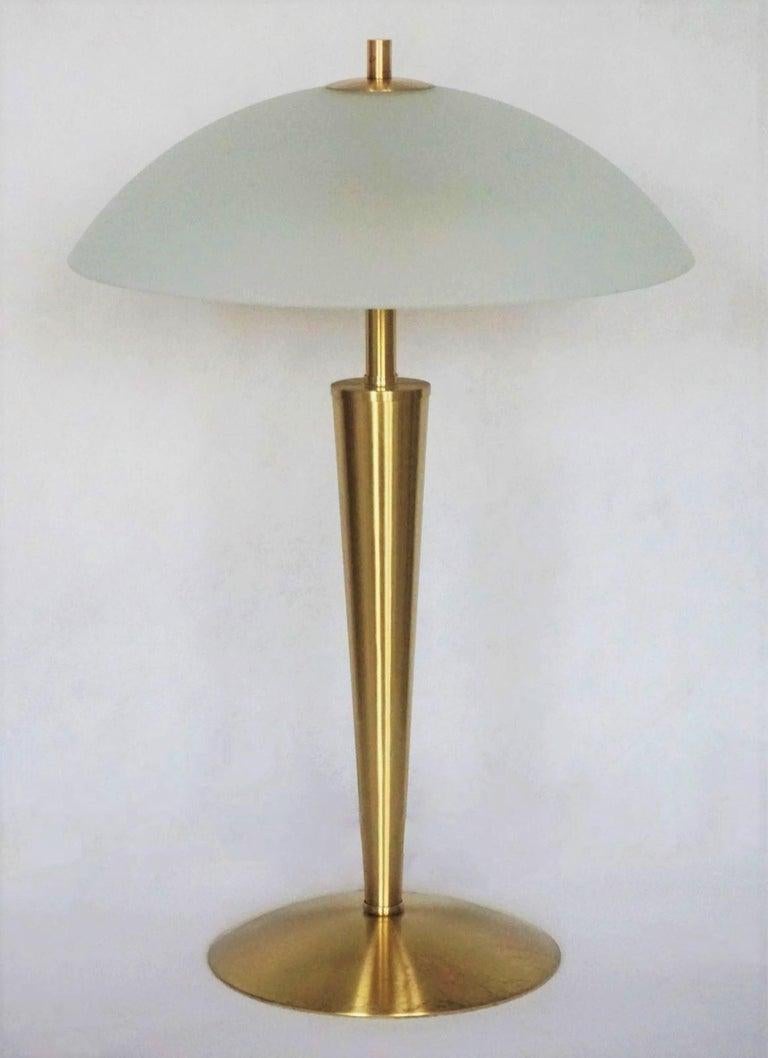 Lampe de table ou de bureau scandinave en laiton à deux lumières, conçue et produite au Danemark dans les années 1960. Lignes épurées et design organique de la période The Scandinavian Modern avec abat-jour en verre satiné. 
Cette lampe est
