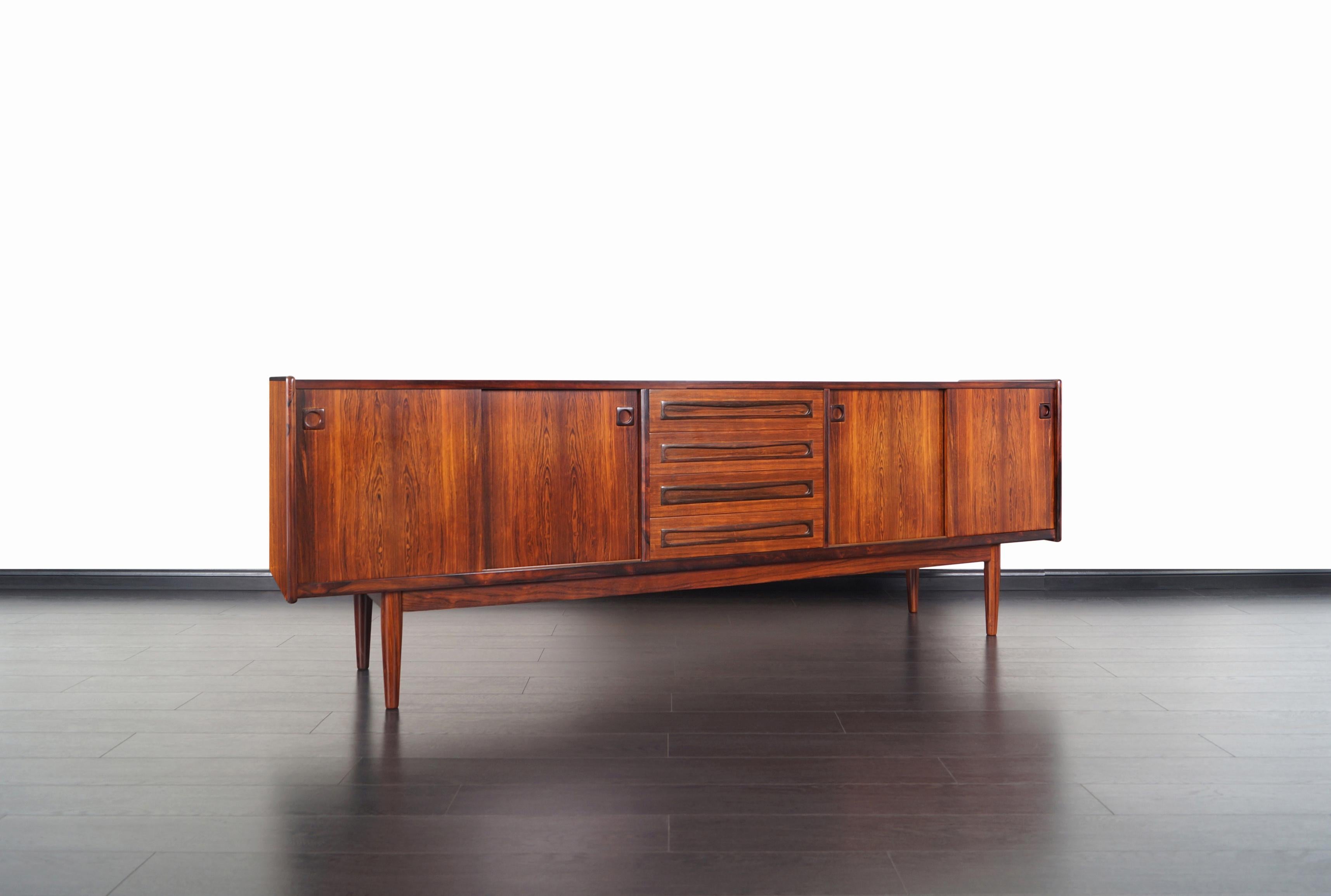 Exceptional Danish Brazilian rosewood credenza designed by Johannes Andersen for Uldum Møbelfabrik, Denmark, 1960s. This skillfully crafted credenza is comprised of sliding doors with adjustable shelves and four dovetailed drawers in the center, all
