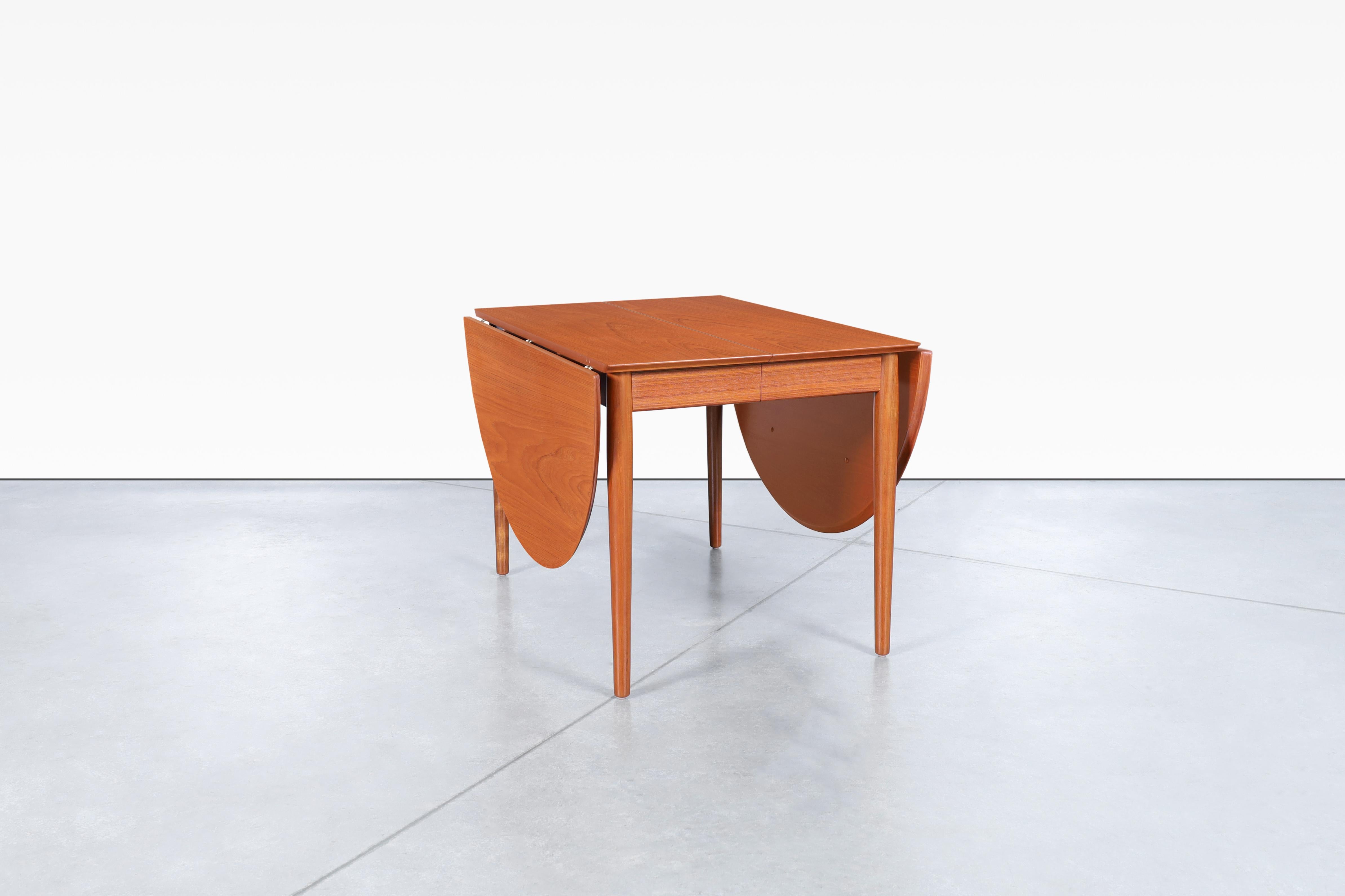 Looking for a statement piece to complement your dining room? Look no further than this stunning Danish modern teak expanding dining table designed by Arne Vodder for Sibast Møbler in Denmark, circa 1950s. The unique drop-leaf design is both stylish