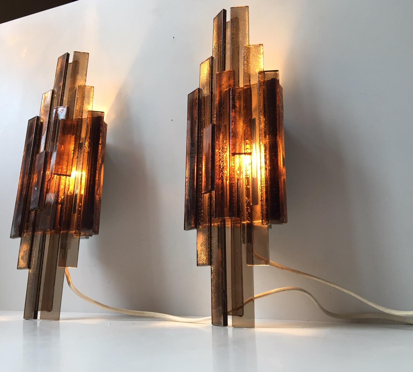 This pair of wall lamps was designed by Claus Bolby and manufactured by his own lighting company Cebo Industri of Silkeborg, Denmark in the late 1960s-early 1970s. The lamps have been constructed from layered strips of smoke-grey acrylic resin. The