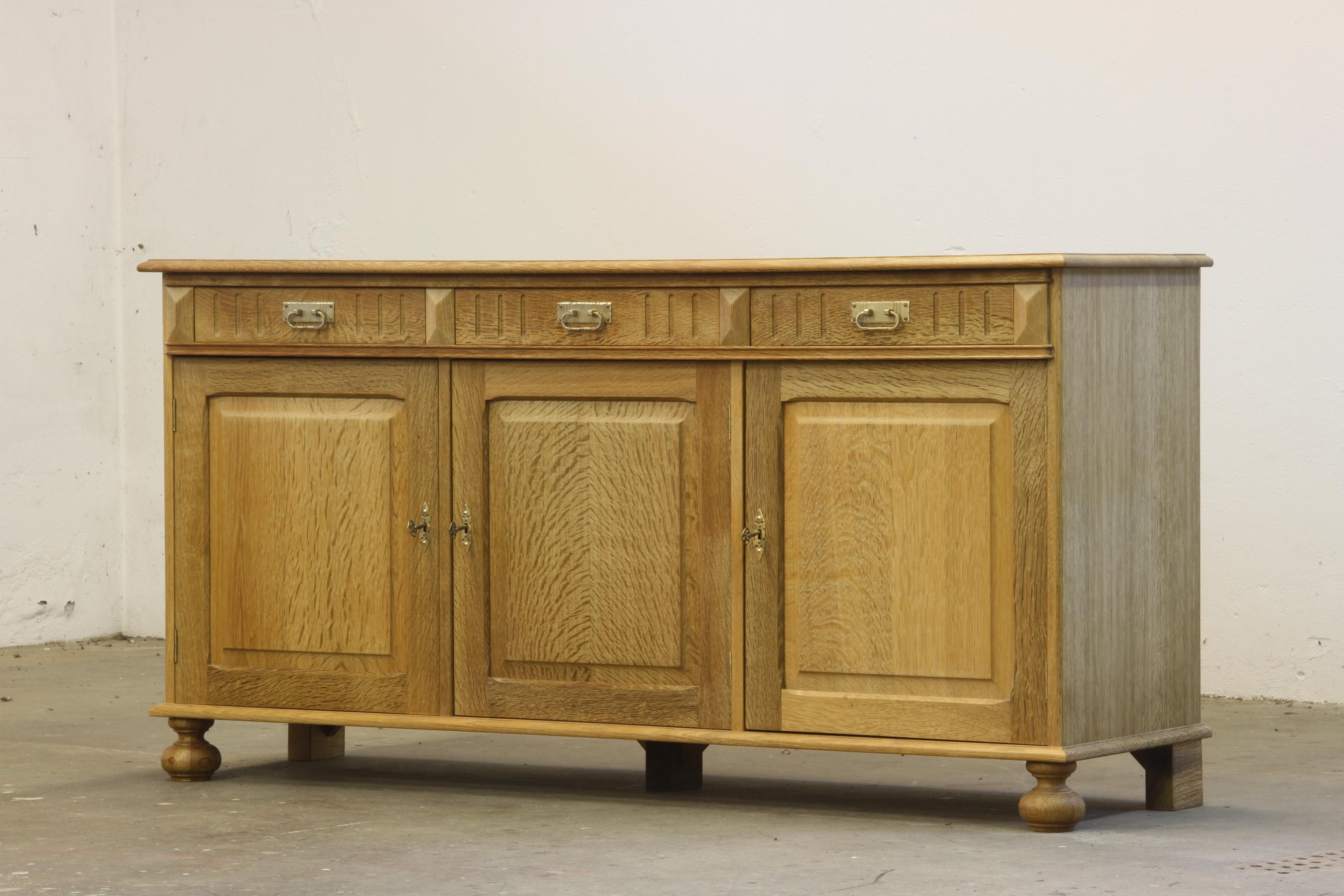A Danish Mid-Century Modern low sideboard in Nordic oak, designed and crafted in Denmark. Often attributed to Henning (or Henry) Kjærnulf, this piece embodies Scandinavian Modern aesthetics with a distinctive 