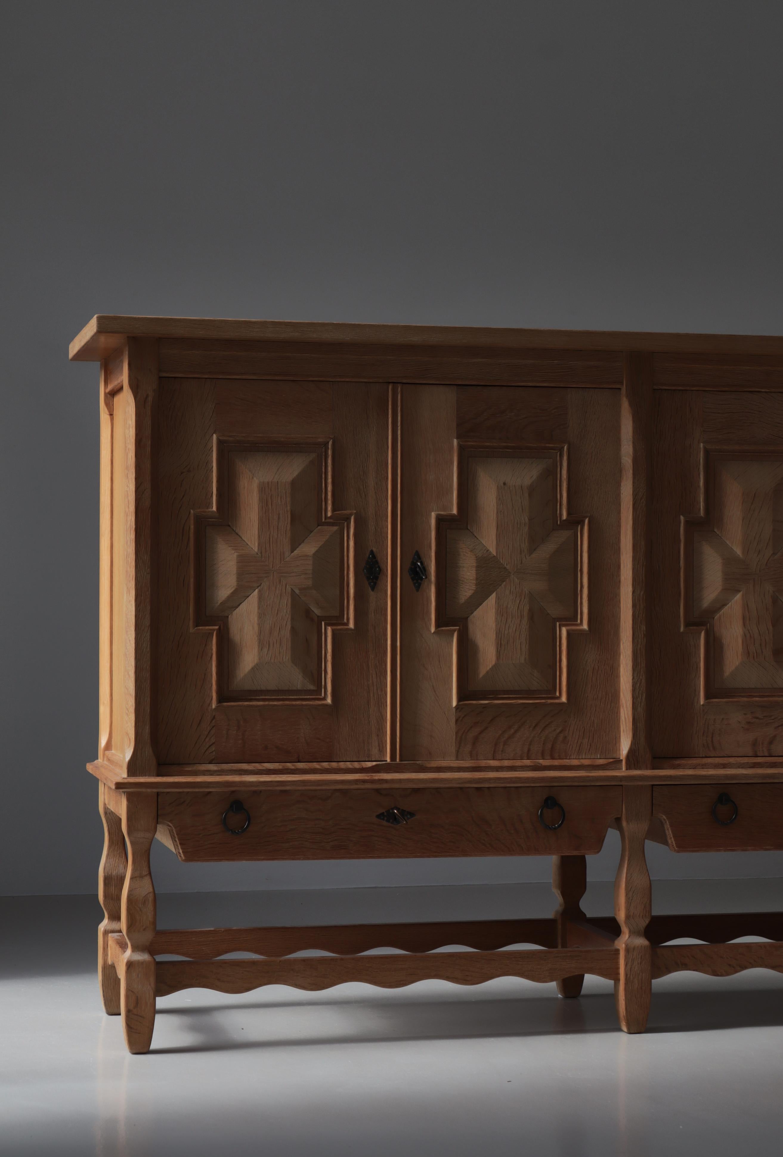 Buffet haut en chêne nordique conçu par Henning Kjærnulf pour Nyrup Møbelfabrik/ EG Kvalitetsmøbler, Danemark, dans les années 1960.  Cette crédence sculpturale offre de nombreux espaces de rangement. Quatre portes à charnières avec des panneaux