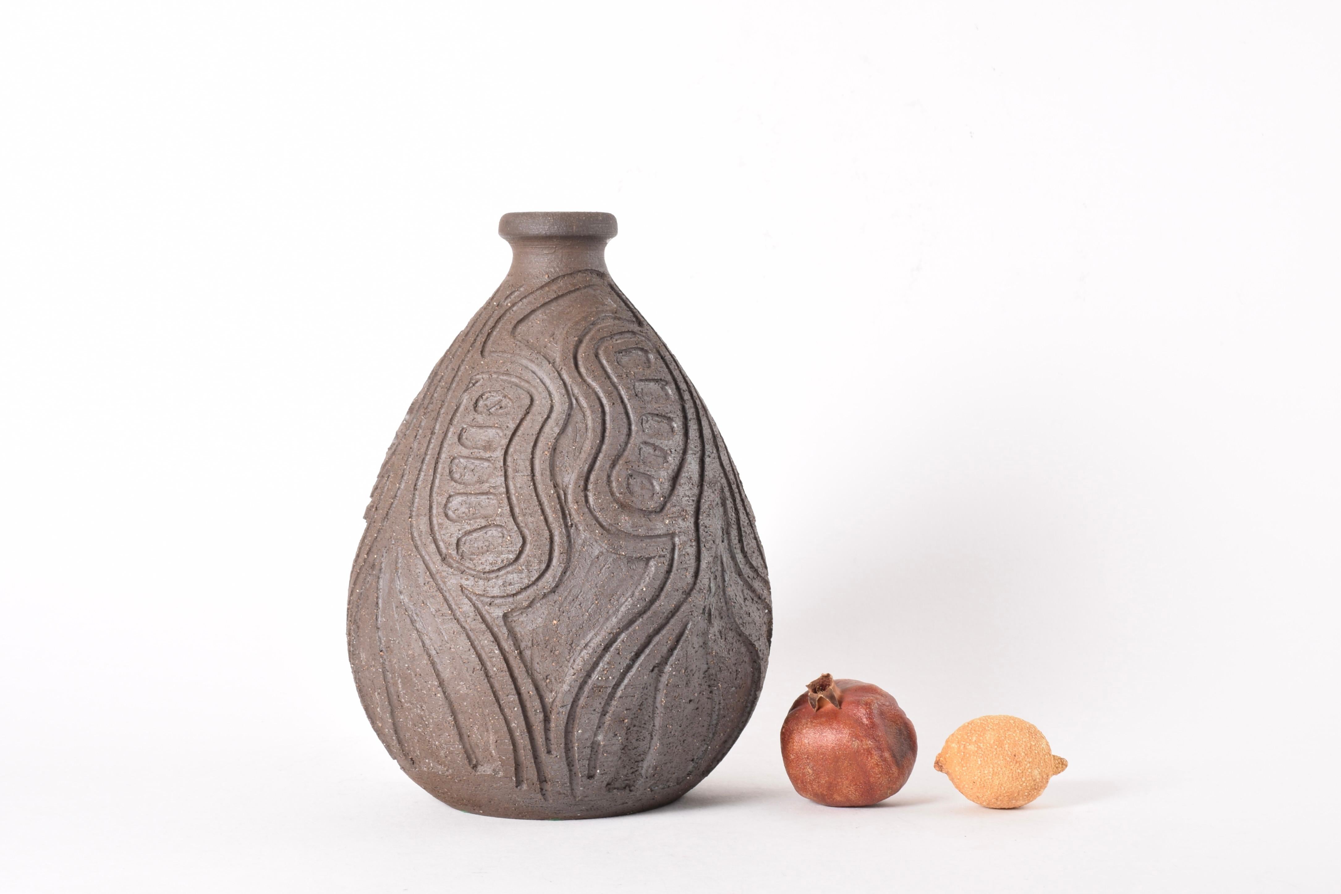 Tall Mid-century Danish vase in Brutalist style by the ceramic studio Løvemose. Made circa 1960s to 1970s.
The sculptural vase is made from unglazed chamotte clay and has a deep hand-carved abstract ornamental decor giving this piece a strong