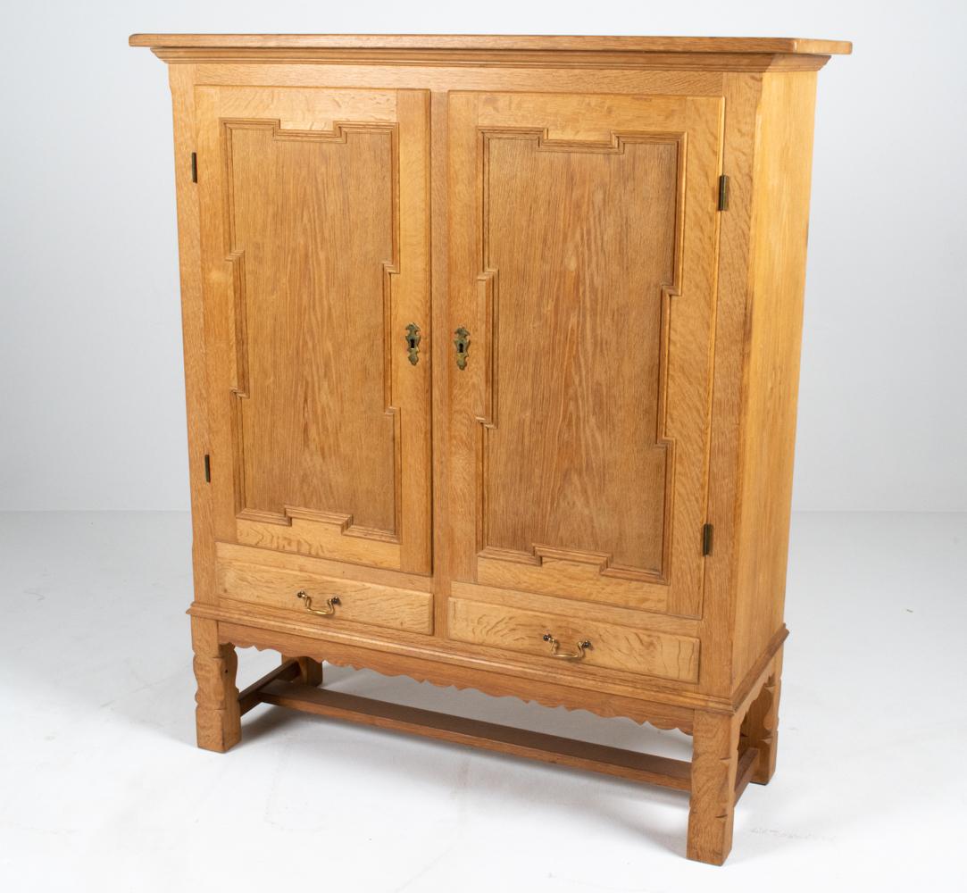 This stately cabinet features many of the iconic elements prevalent in Henning Kjærnulf's work - including hand-sculpted legs, a plain scalloped apron, antique-inspired brass hardware simplified for a Modern look, and gorgeous quarter-sawn white oak
