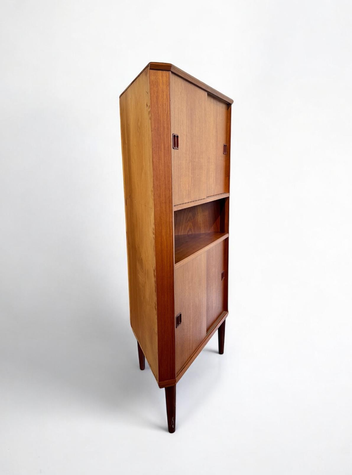 Elegant 1960's Danish Teak corner cabinet crafted beautifully, it has four sliding doors and adjustable shelves, combining style with functionality with generous storage space. 