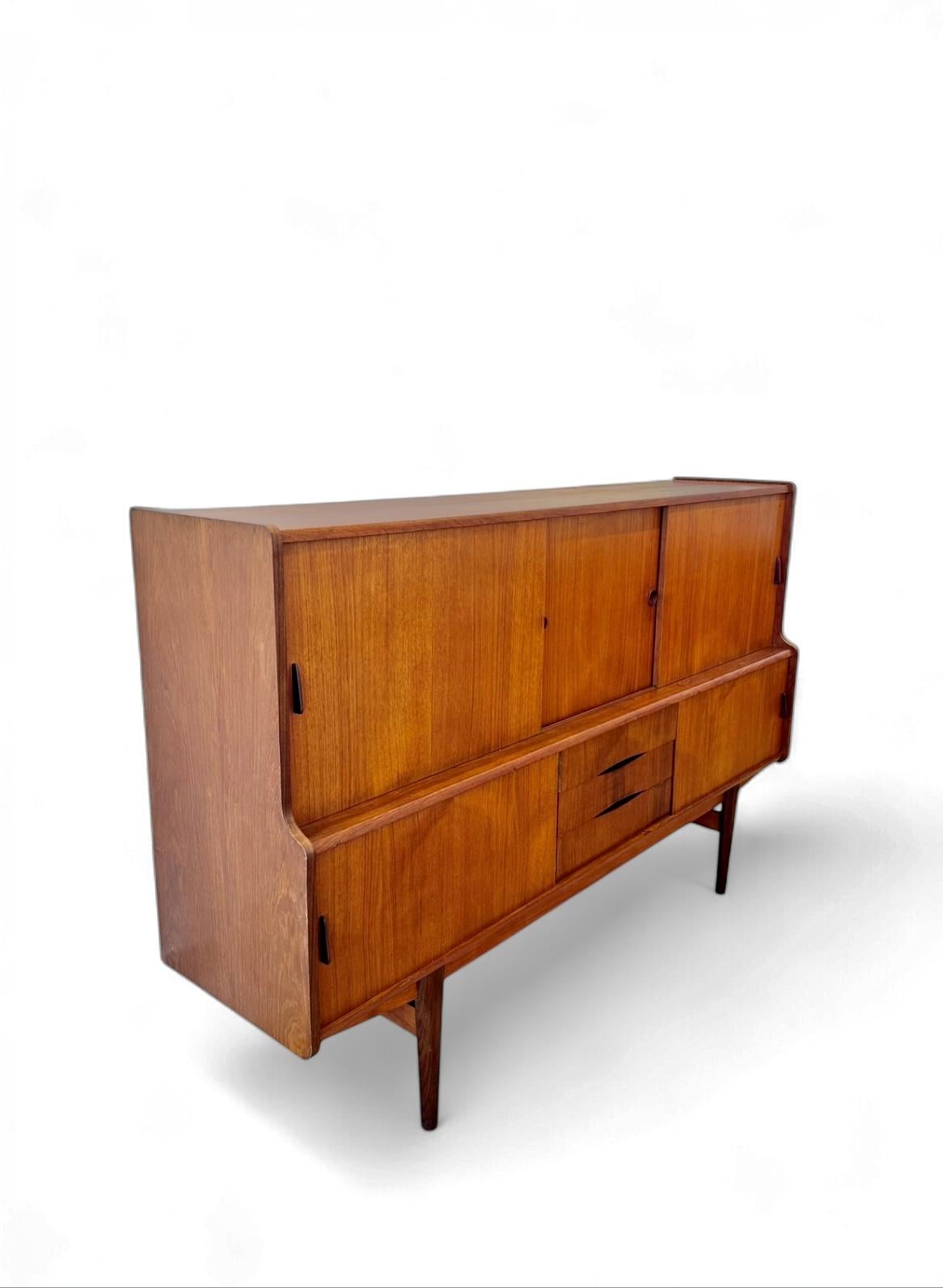 Danish Teak Credenza Highboard by ES Mobler from the 1960s, made in Denmark, this piece features beautiful Teak wood and Mid Century Modern minimalist elegance with lots of storage. The centre compartment has one shelf to acommodate cocktail glasses