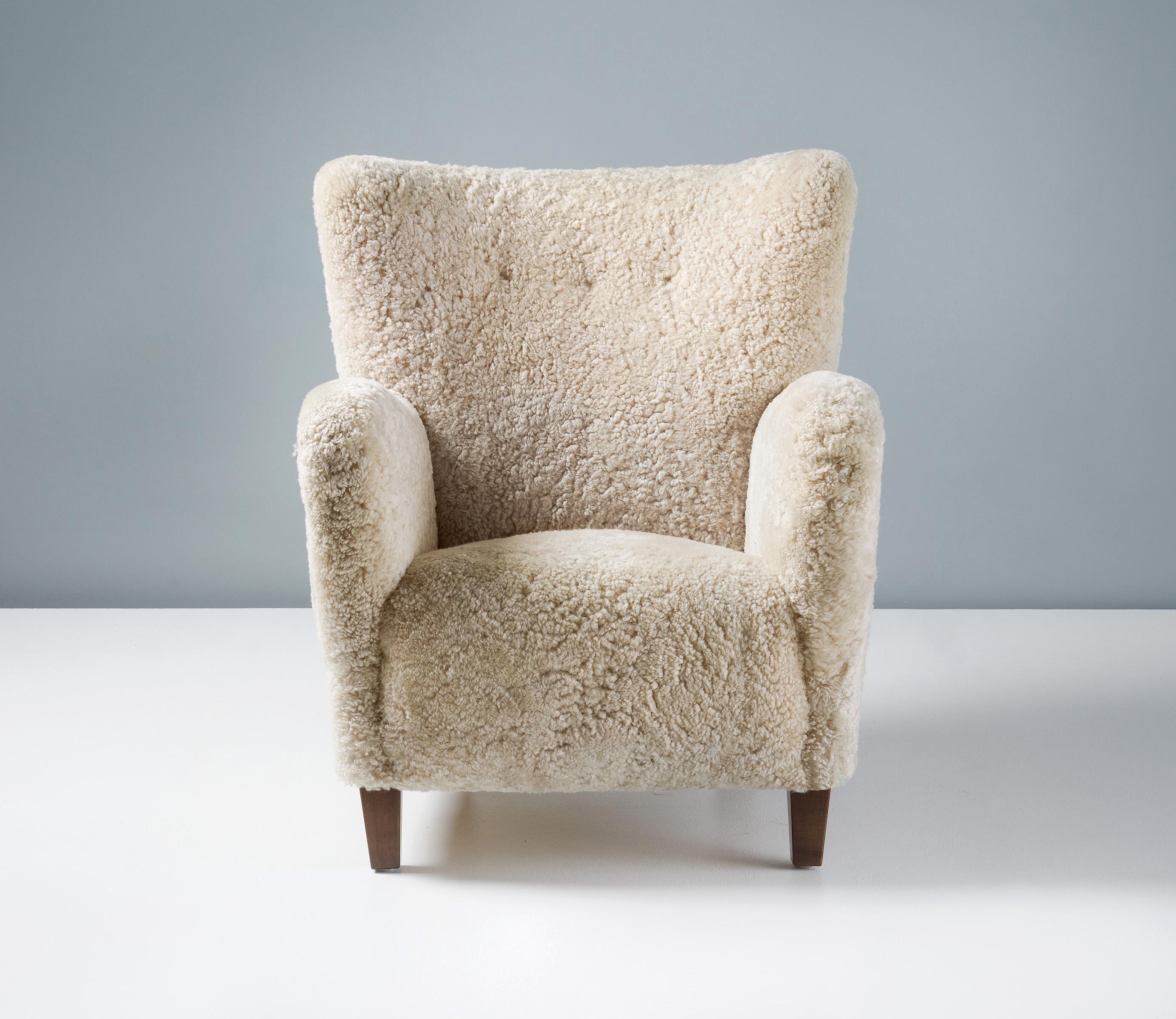 Danish Cabinetmaker Sheepskin Lounge chair, circa 1940s.

Lounge chair in the manner of Fritz Hansen produced in Denmark in the 1940s, featuring wonderfully curved arms and back and taper beech wood legs. The chair has been reupholstered in