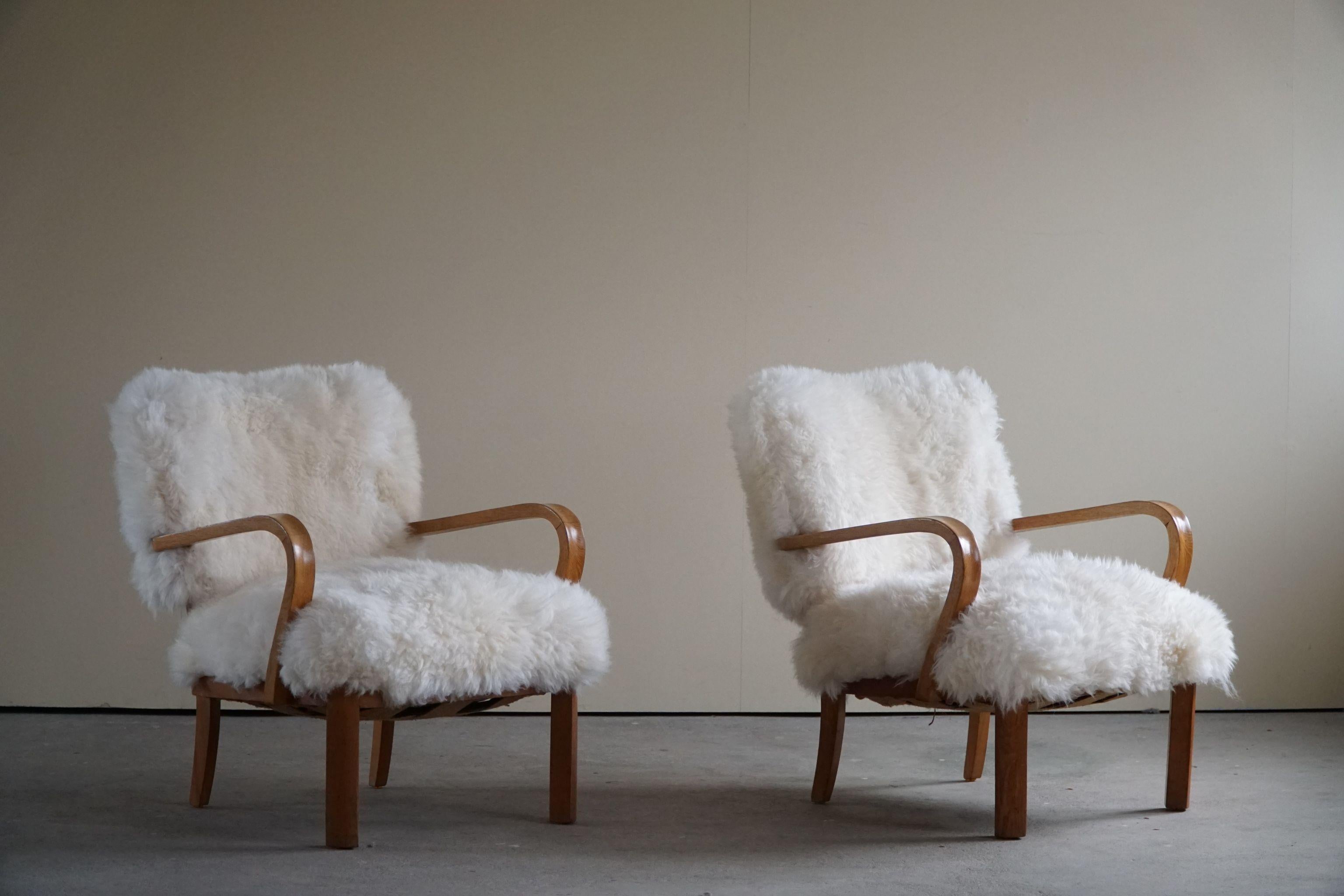 A pair of mid century lounge chairs, reupholstered in long-haired lambswool with a oak frame. Made by a Danish cabinetmaker in 1950s. 

With a heavy focus on functionality, this design style leans toward modernism, while incorporating coziness. The