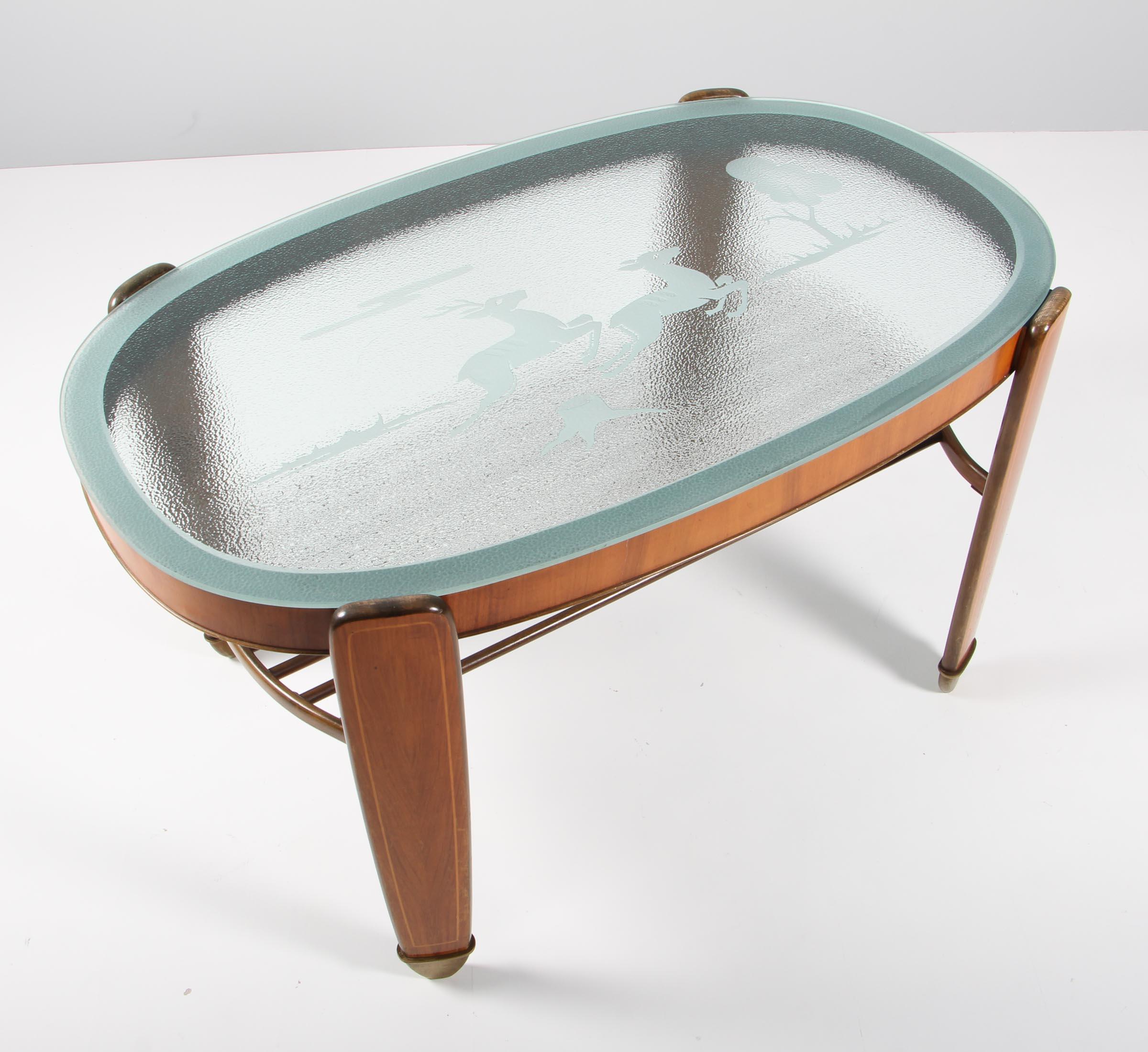 Danish cabinetmaker Art Deco coffee table with nutwood frame with intarsia details. Shoes of brass.

Glass plate with details of a person and a horse.

Made in the 1930s.