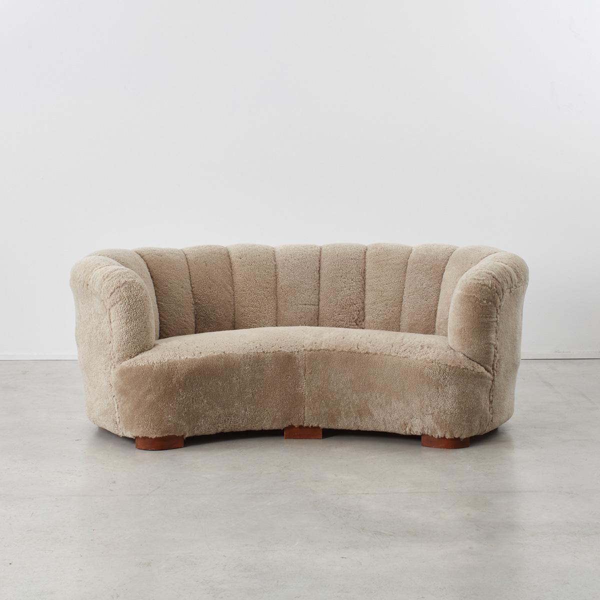 Early 1940s Danish Banana three-seat sofa in the manner of architect Flemming Lassen, newly reupholstered in genuine sheep’s pelts. The sofa is of excellent craftsmanship, probably made by Slagelse Møbelværk, Denmark using proper materials, solid
