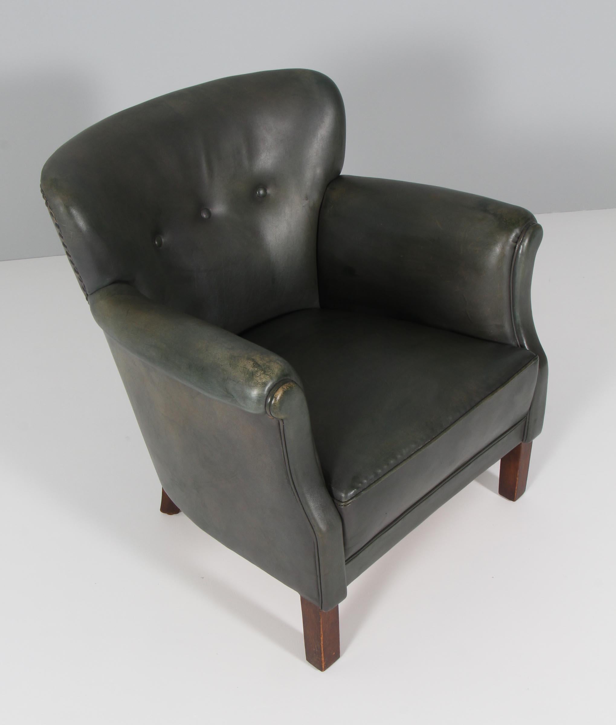 Danish cabinetmaker club chair in original green patinated leather.

Legs of stained beech.

Made in the 1940s.