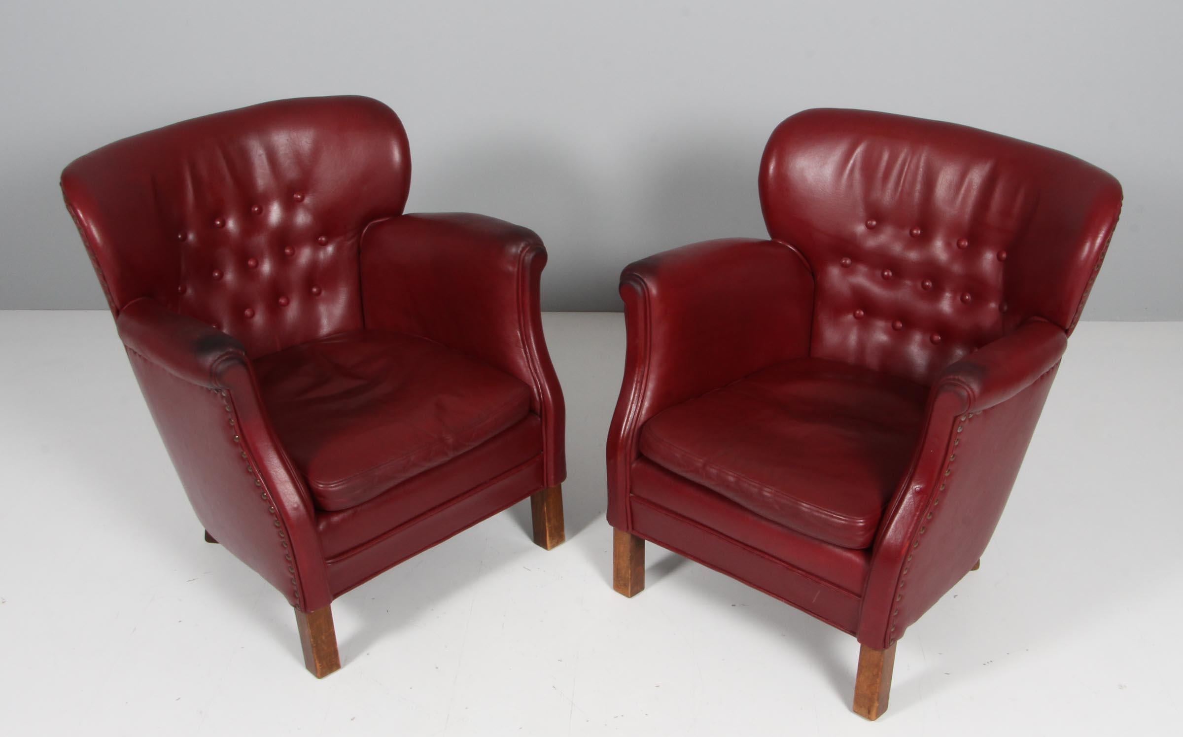 Danish cabinetmaker club chair in original red leather.

With buttons.

Legs of stained beech.

Made in the 1940s.