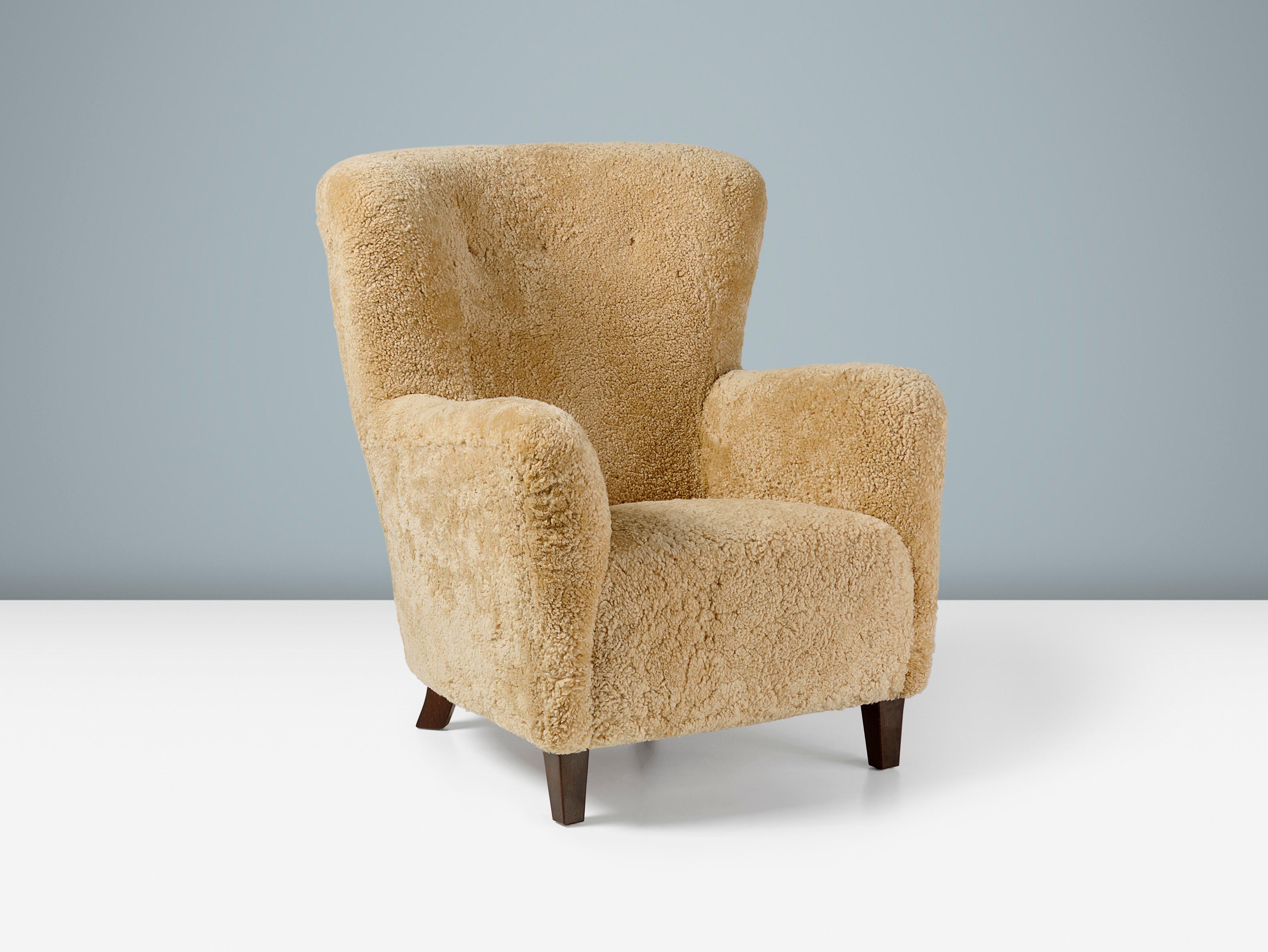 Danish Cabinetmaker Sheepskin Armchair, circa 1940s.

This tall lounge chair produced by a Danish Cabinetmaker in the 1940s is typical of Danish lounge chair designs of the day. It features a slightly curved wing-back with angular arms and straight,